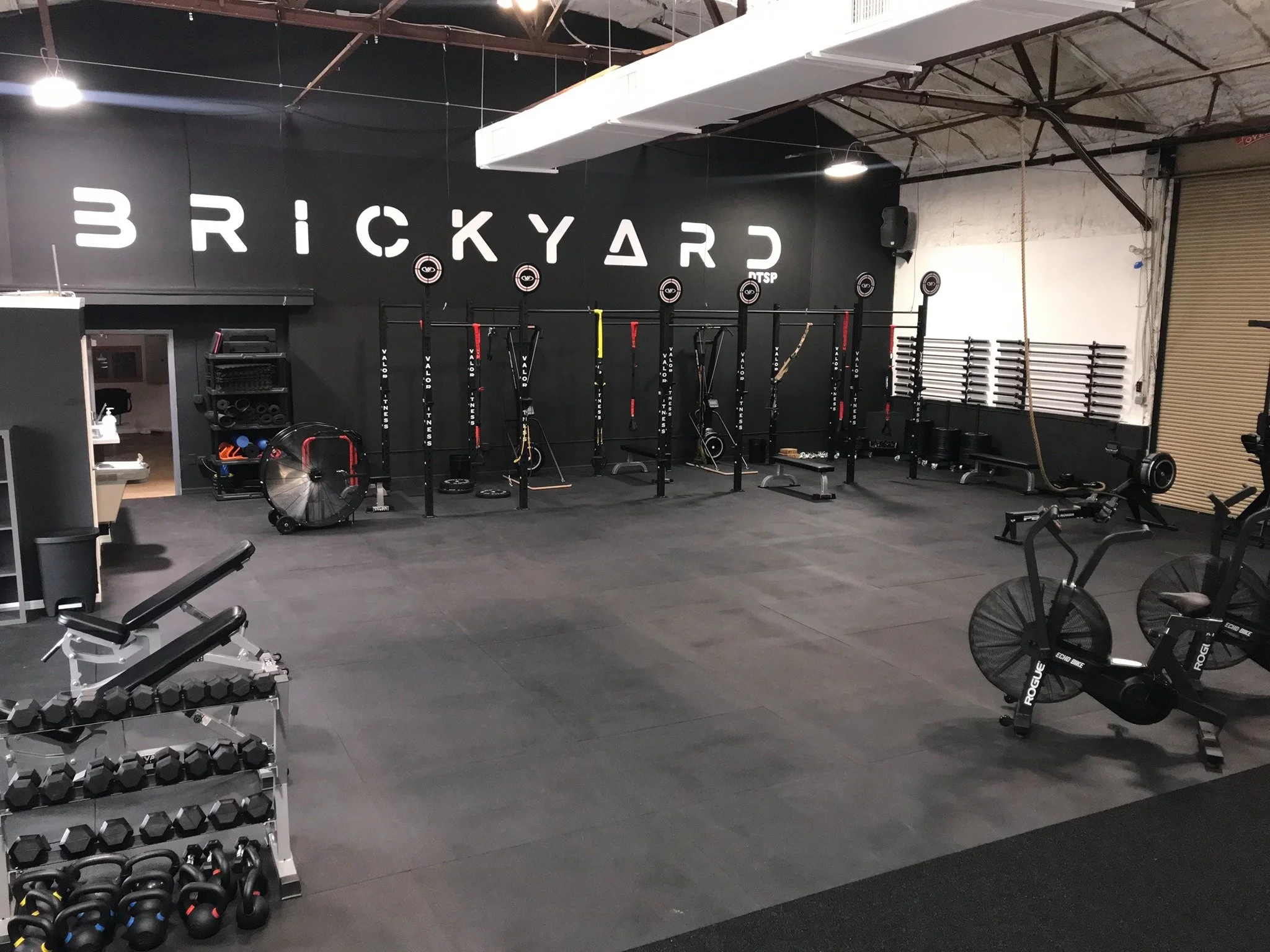 Interior of Brickyard Gym in St. Pete with weight racks, cardio machines, and functional training equipment in a modern industrial space.
