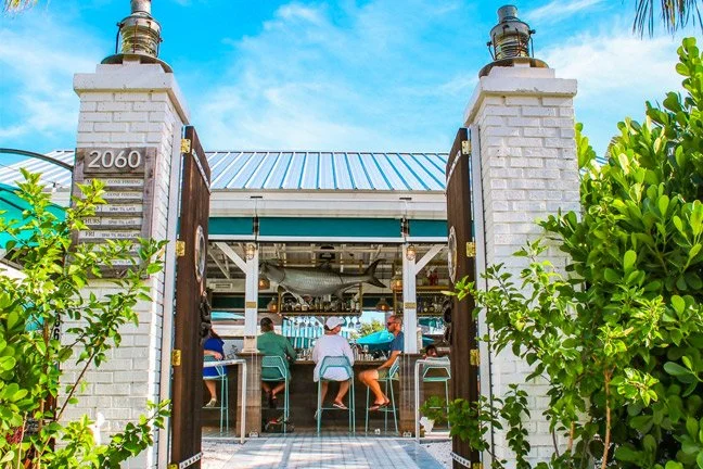 Outdoor entrance and bar seating at Trophy Fish seafood restaurant in downtown Saint Petersburg, Florida, a popular stop by golf cart