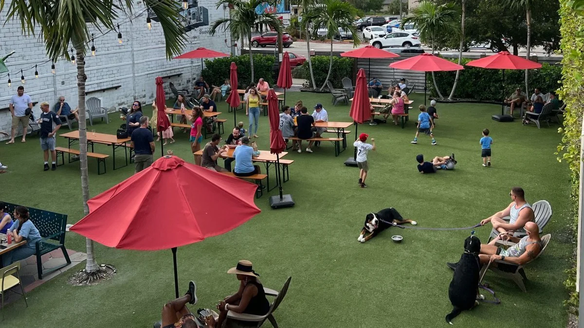 People and dogs relaxing at Green Bench Brewery's outdoor beer garden in downtown St. Petersburg, Florida.