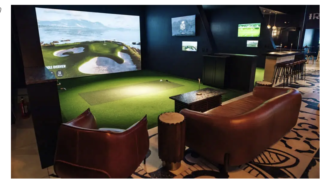 Indoor golf simulator lounge at The Irons Club in downtown St. Petersburg, Florida with large screen and seating area