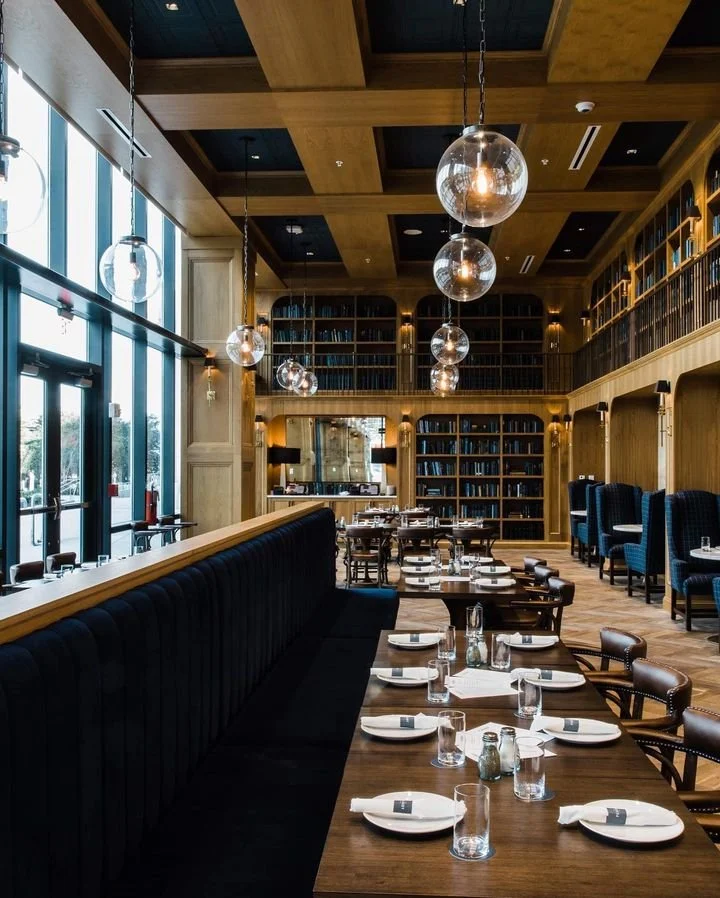 Interior of The Library restaurant in St. Pete with tall bookshelves, warm lighting, and elegant tables set for brunch.
