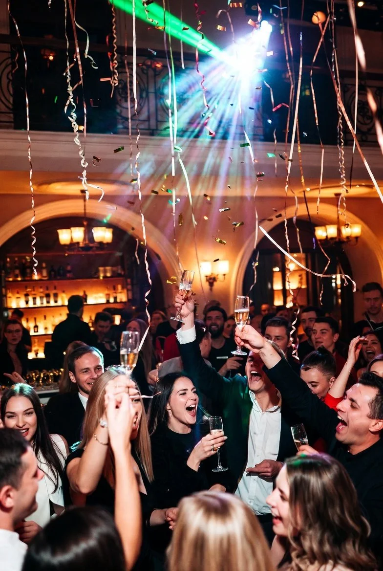 Crowd celebrating New Year’s Eve at Park and Rec DTSP with champagne toast, confetti falling, and high energy disco masquerade party atmosphere in downtown St. Petersburg Florida