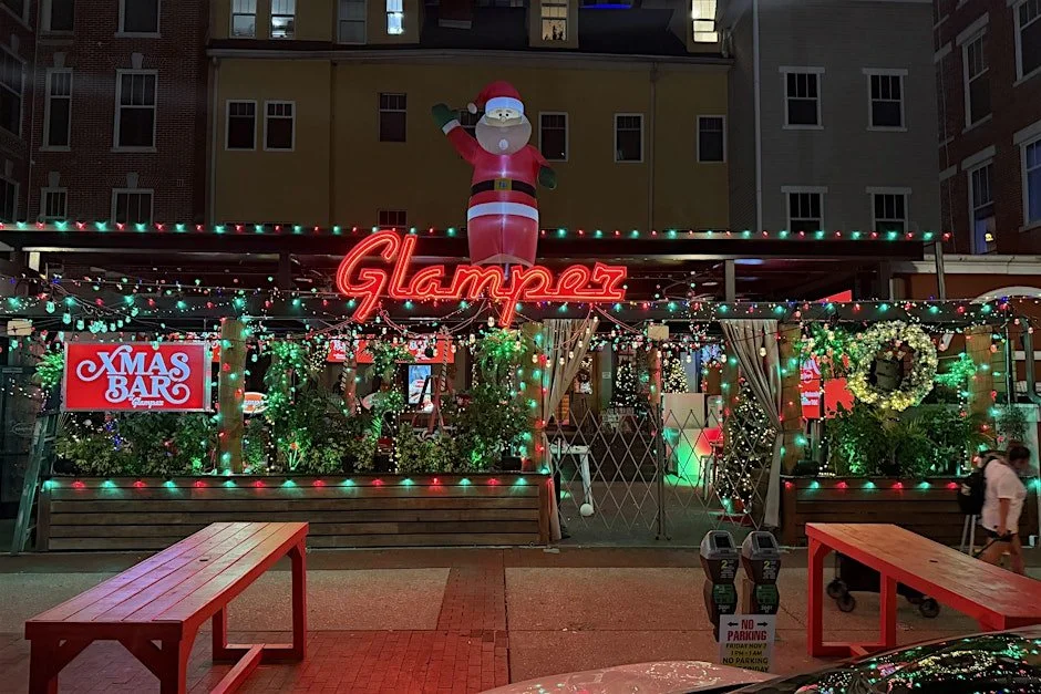 Festive Christmas pop-up bar at Glamper in downtown St. Pete decorated with lights, wreaths, and a large inflatable Santa.