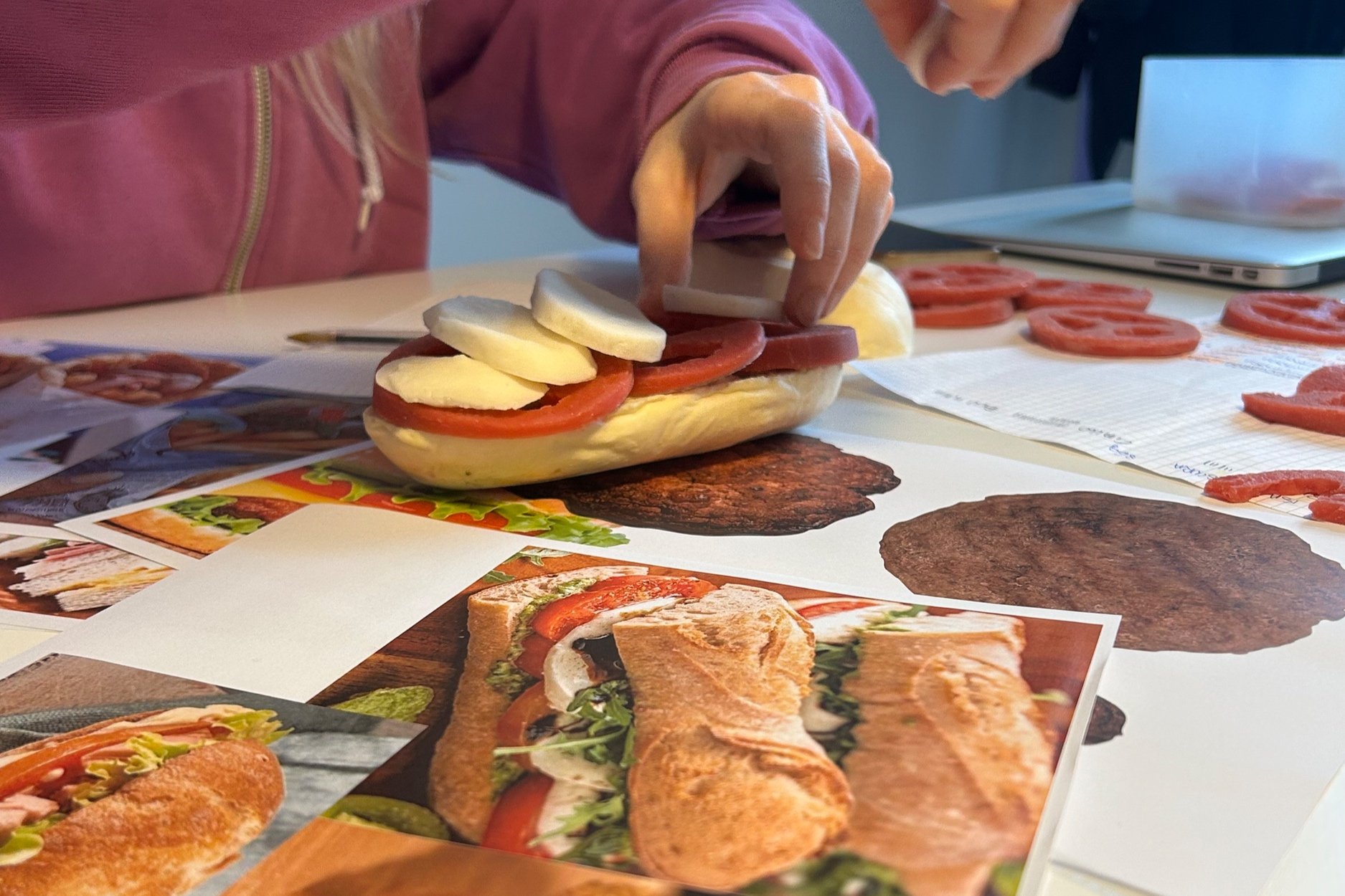 Persona che prepara un panino con pomodoro e mozzarella finti