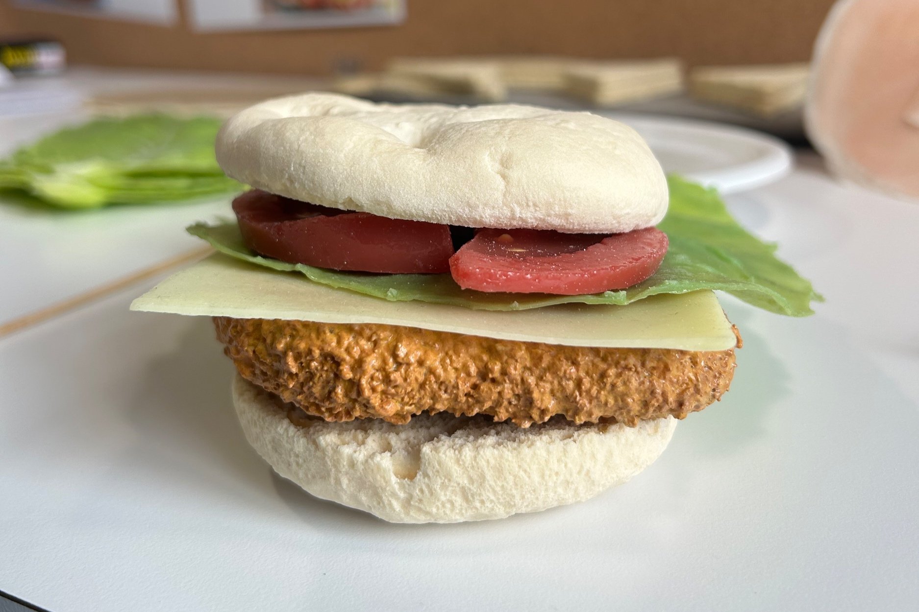 Panino con cotoletta croccante, formaggio, lattuga e pomodoro finto, work in progress