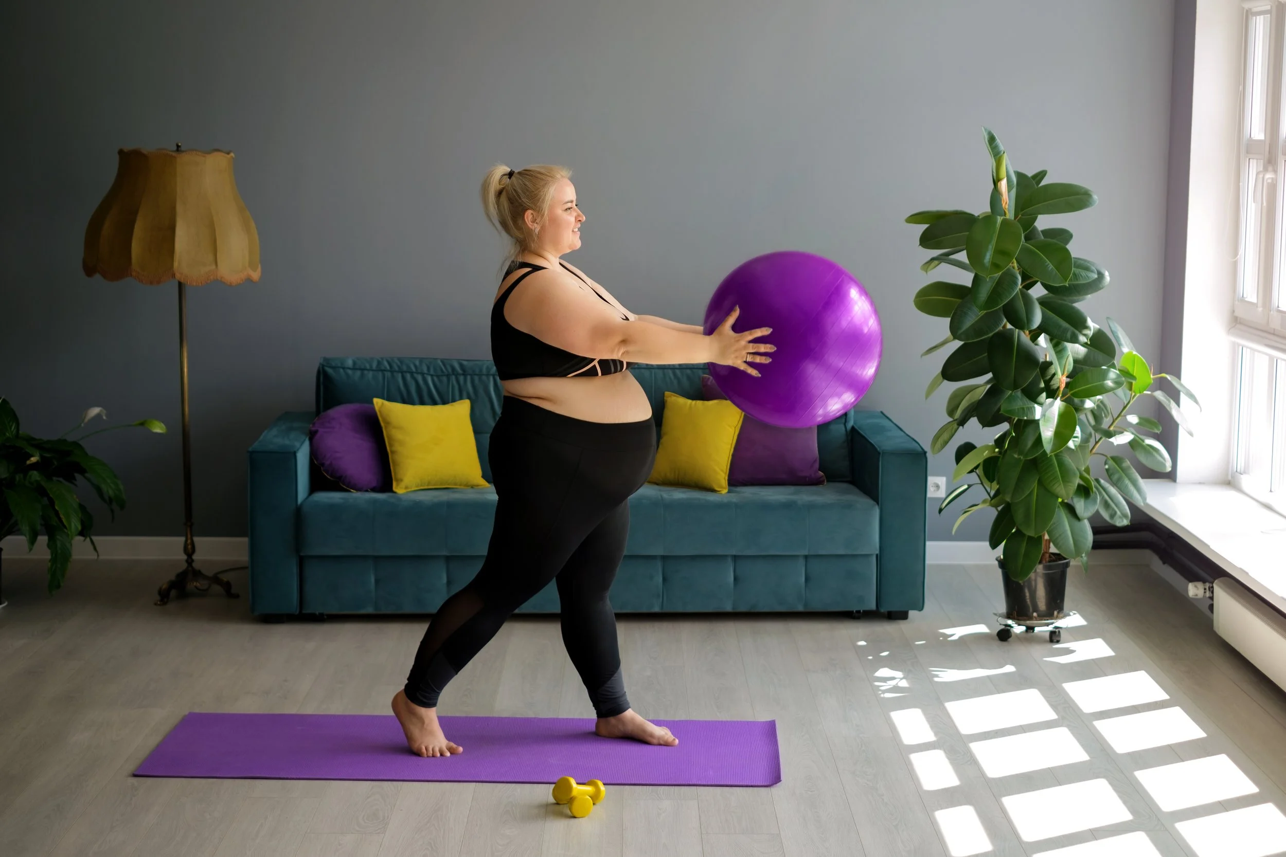 Large pregnant woman using yoga ball