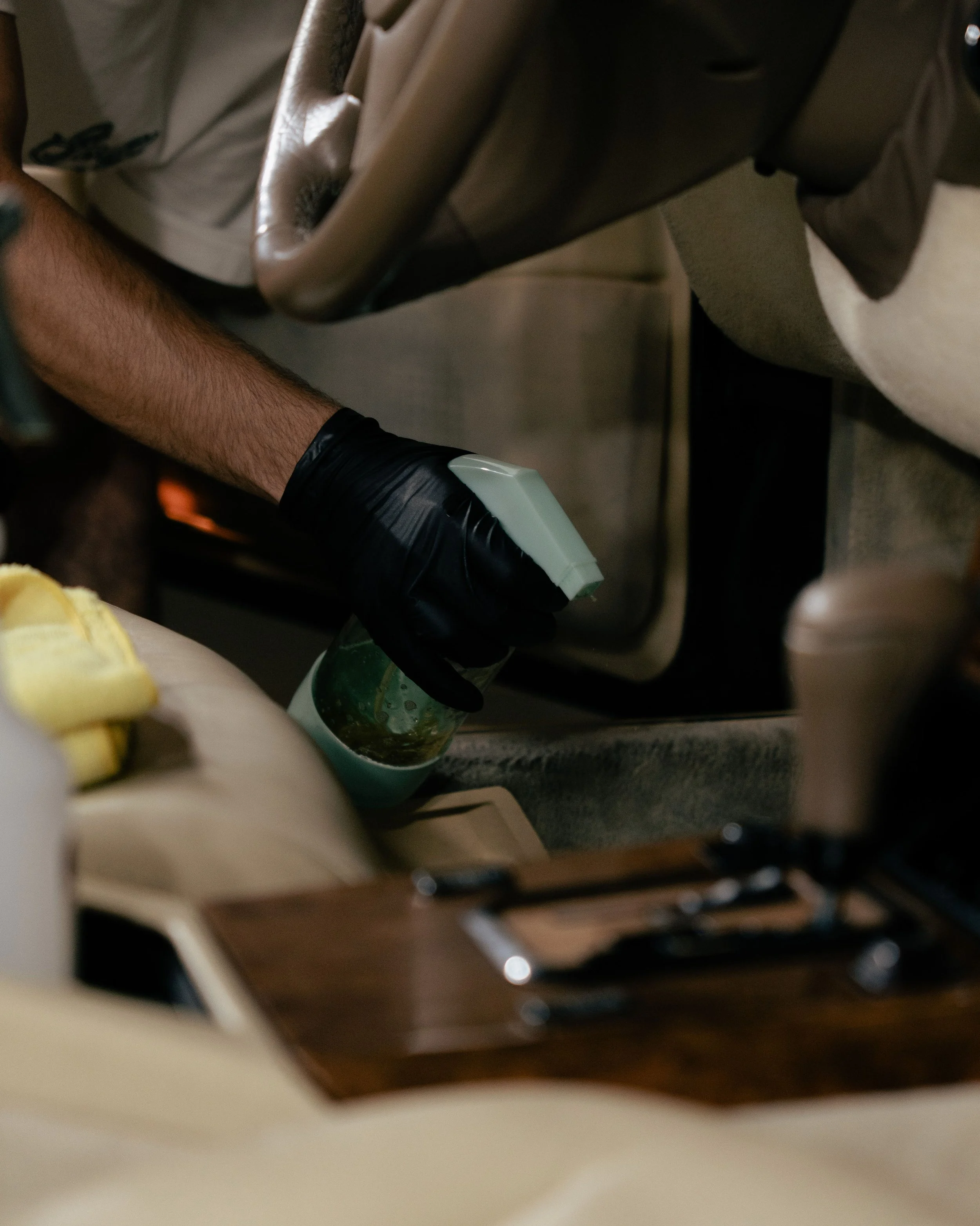 A person wearing a black glove holding a small container of marijuana while sitting in the back of a car.