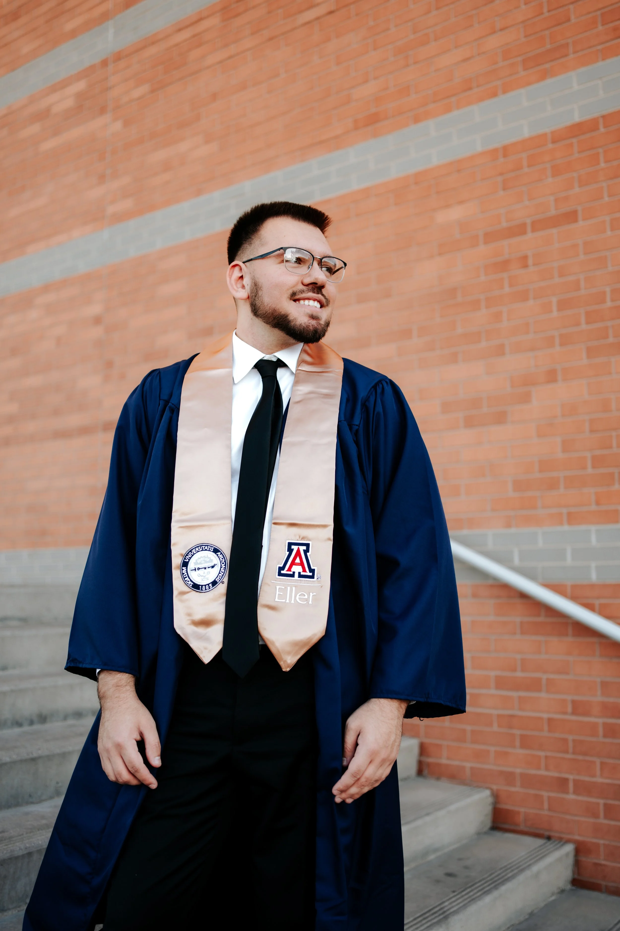 A man stands in front of Eller Business College at the University of Arizona for a college graduation photoshoot.