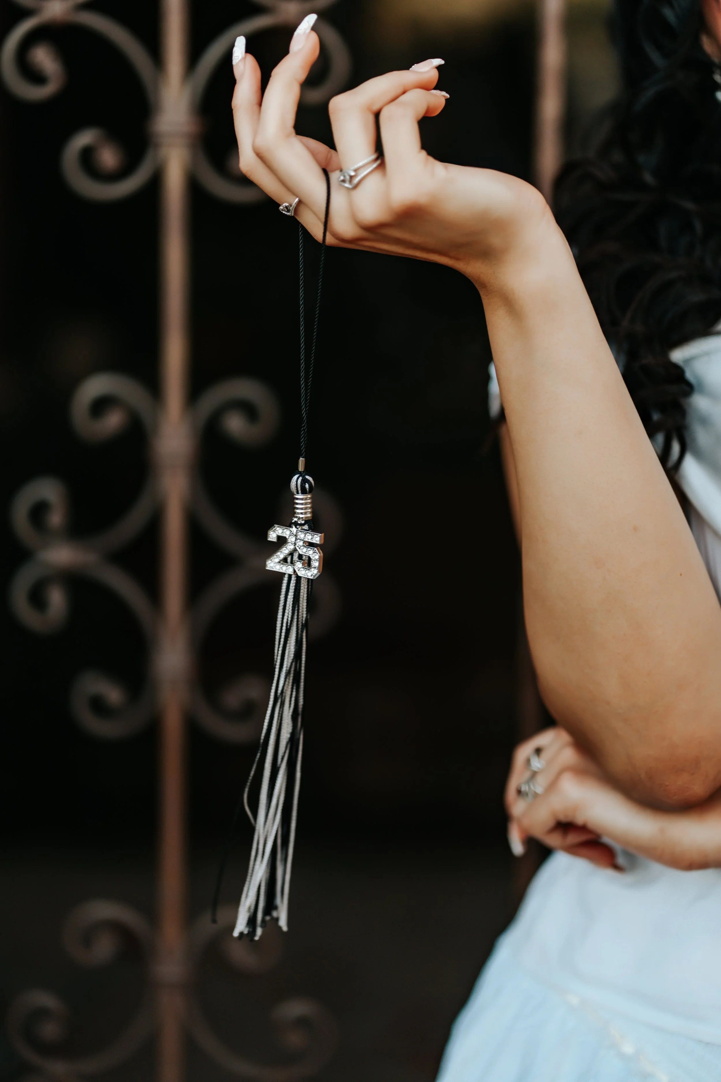 A woman wearing silver rings holds her class of 2025 tassel for a graduation photoshoot in Tucson, Arizona.