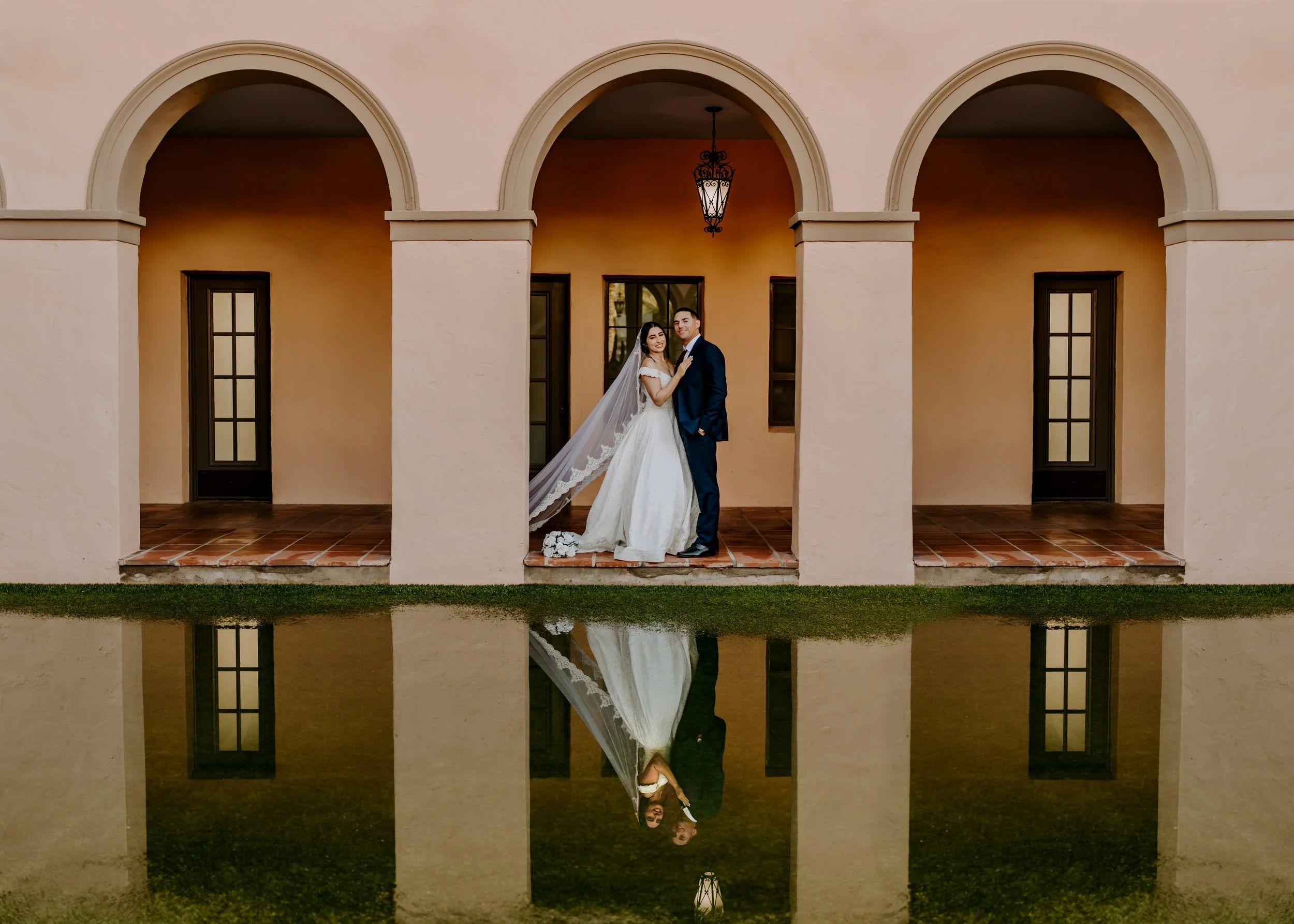 A couple getting married stands in front of the Tucson Historic Courthouse smiling for a elopement photoshoot.