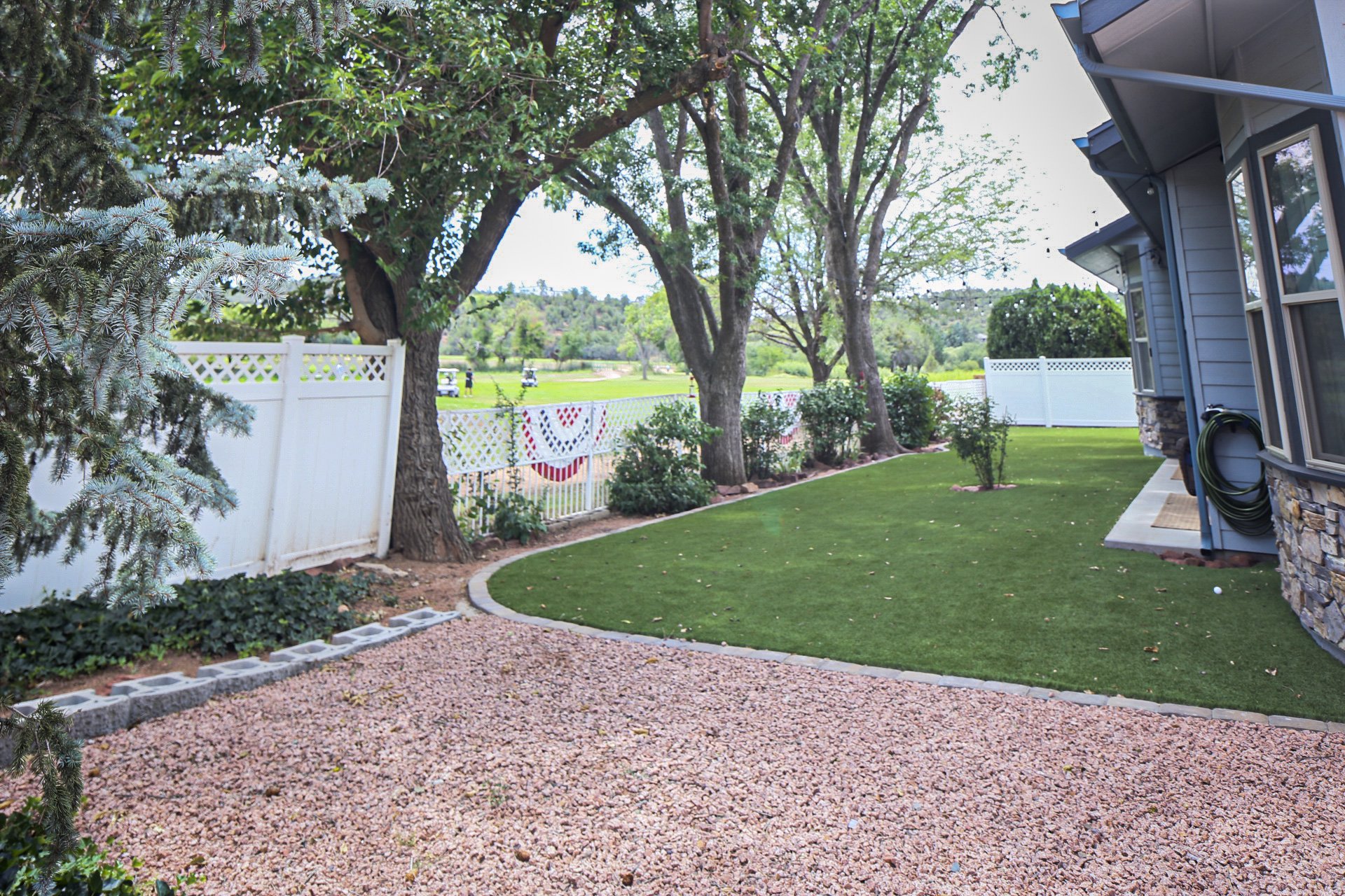 Backyard with artificial grass, gravel area, trees, white fence, and expansive view of Payson Golf Course