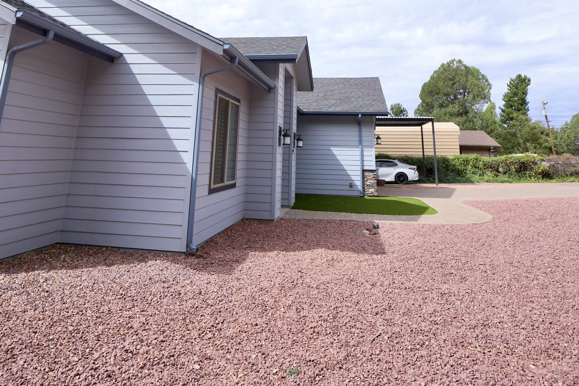 Exterior of the house in the front yard featuring a gravel yard, driveway parking for 2 vehicles, and oversized covered parking structure.