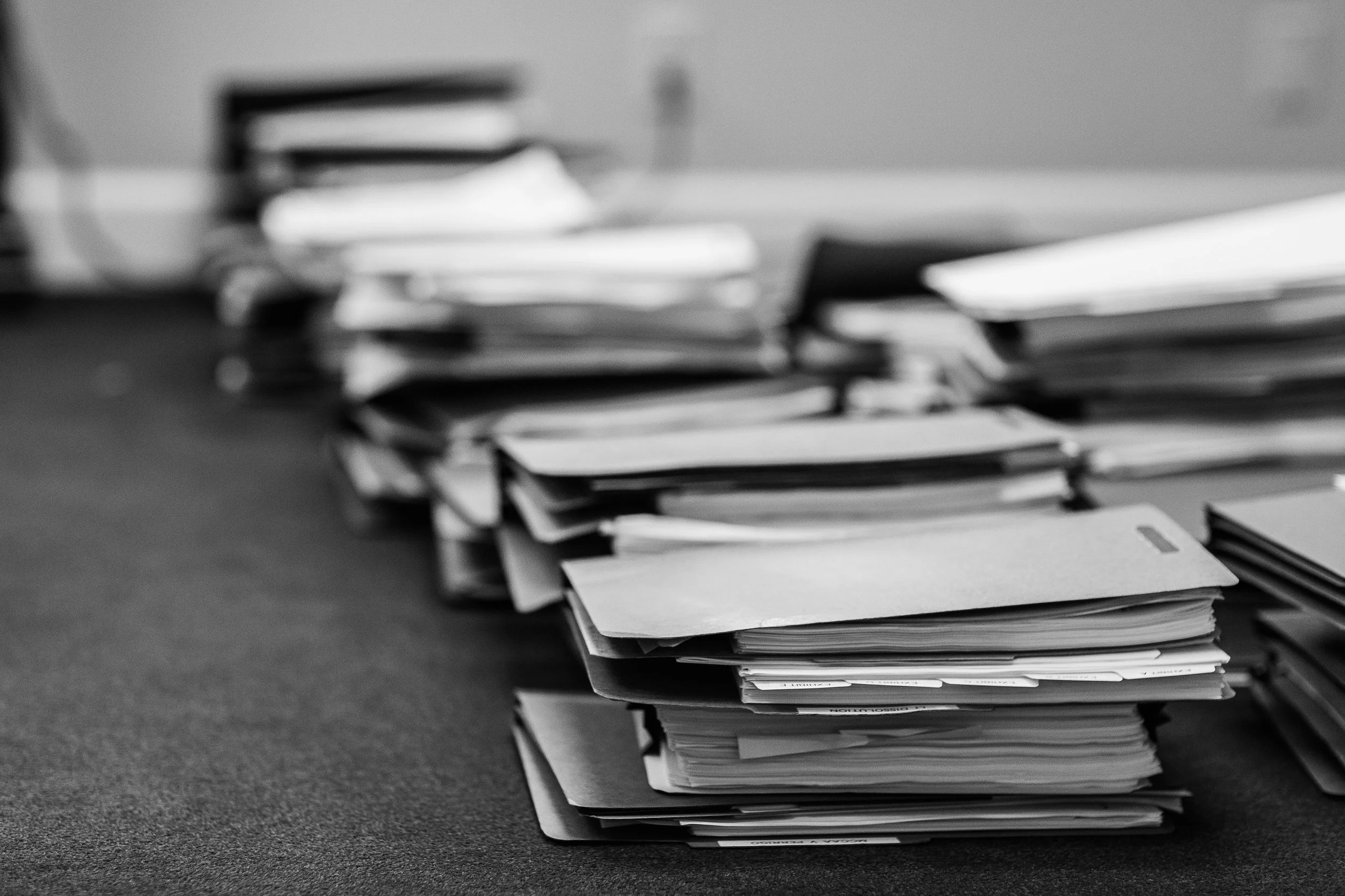 A large pile of manila folders and paperwork on a desk in an office.