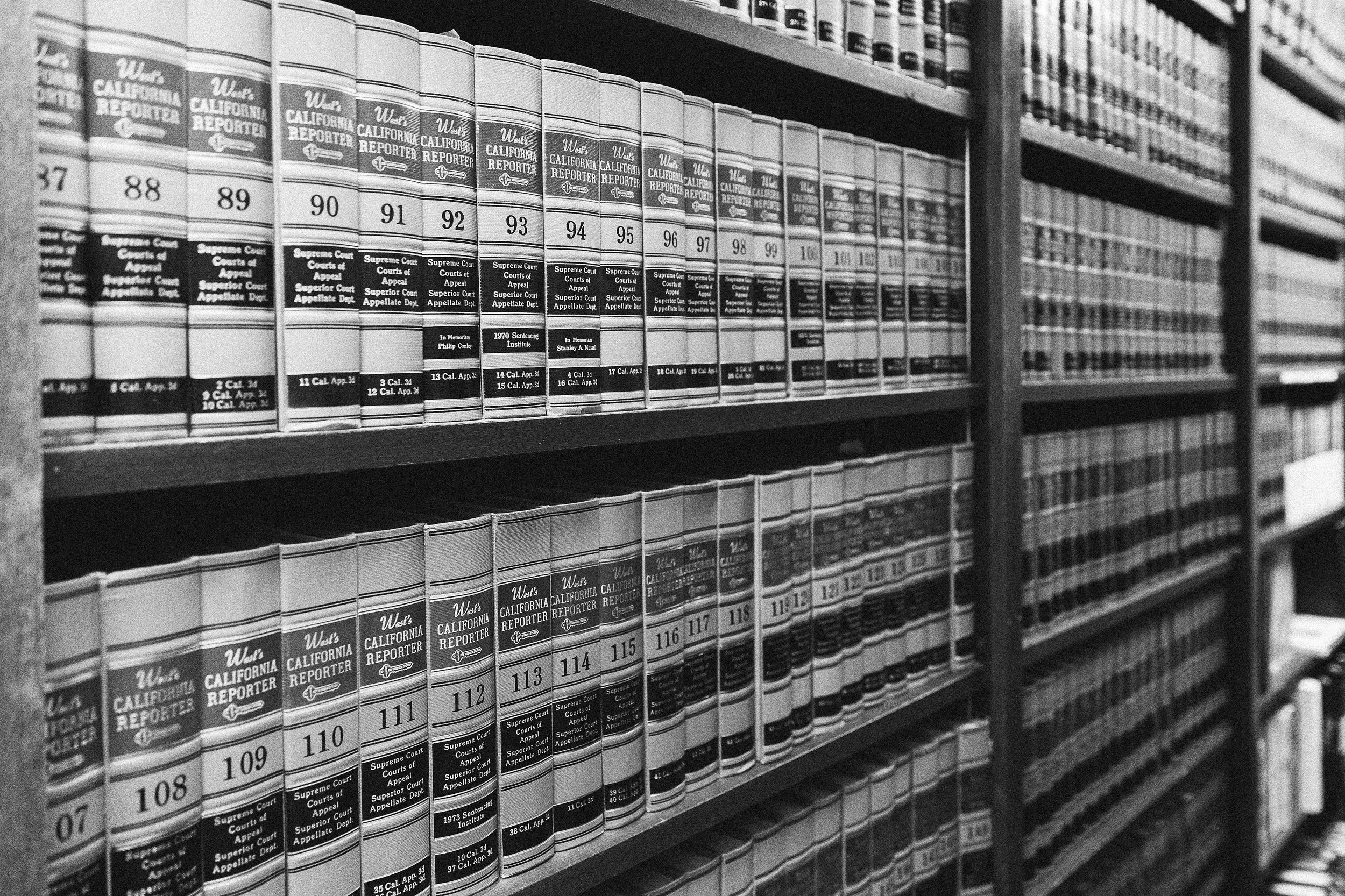 A black and white photo of shelves filled with volumes of legal reference books, titled 'West's California Reporter,' organized by volume numbers.