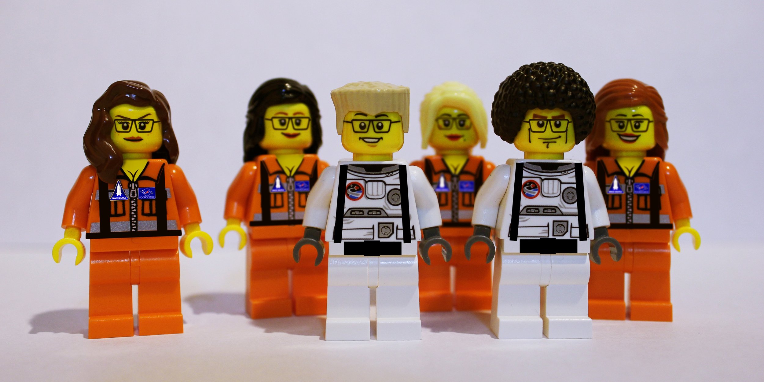 Six LEGO minifigures dressed as astronauts standing in a row, with three in orange space suits and three in white space suits, against a plain white background.