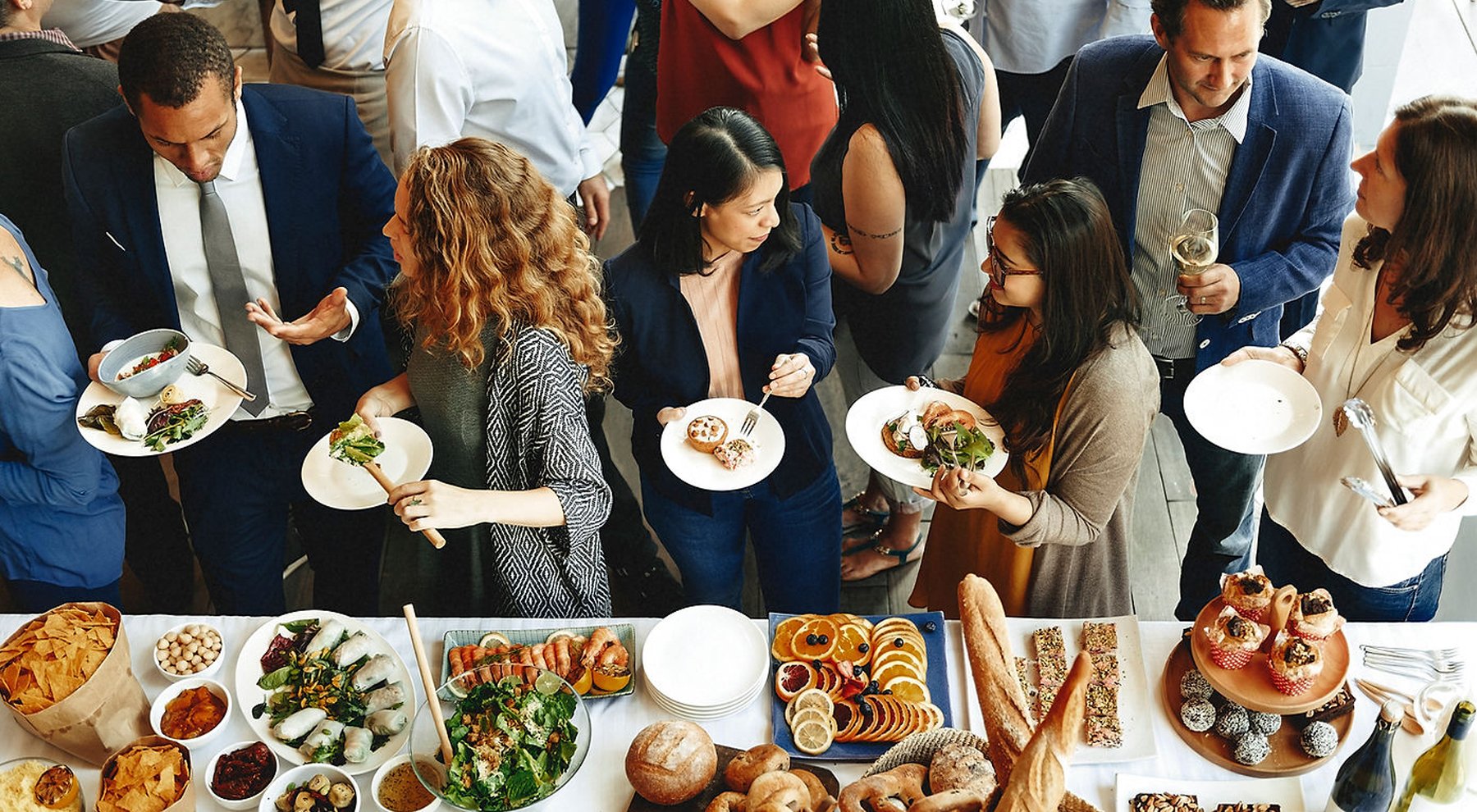 People at a buffet table with various appetizers and desserts during a corporate gathering.