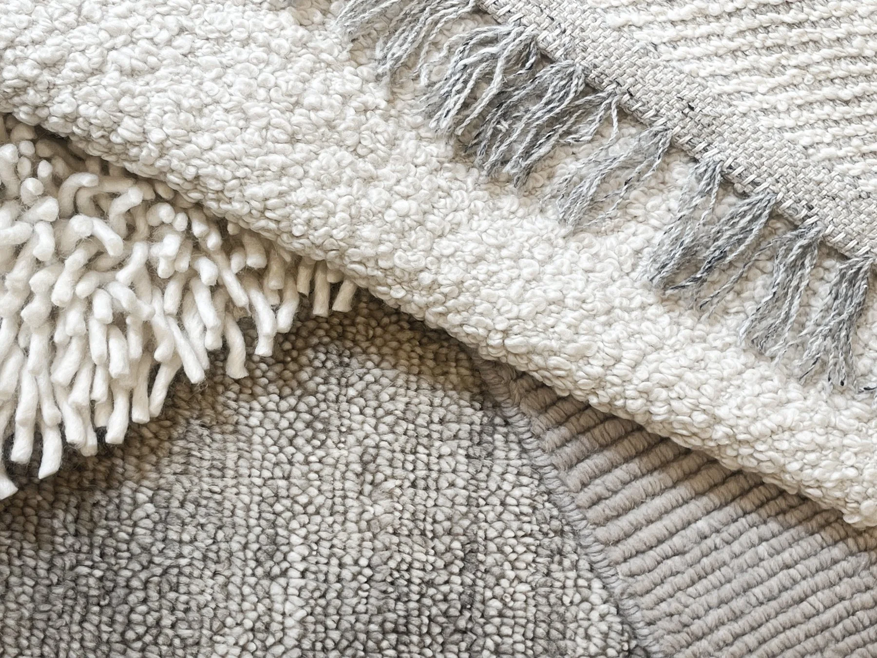 Close-up of woven and knit textured blankets and throws in neutral tones.