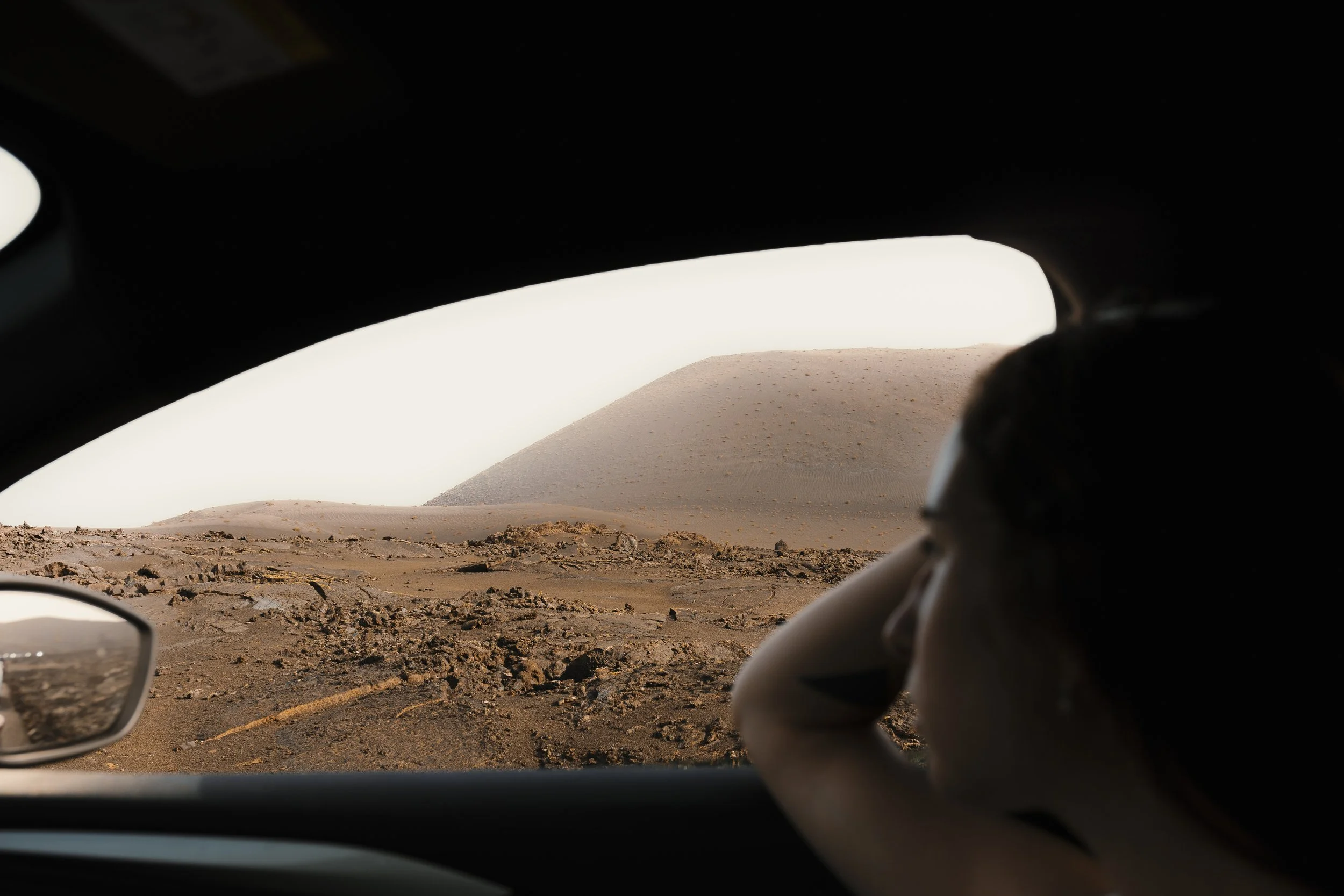 Persona che guarda un paesaggio desertico, probabilmente su Marte, attraverso un finestrino di un veicolo