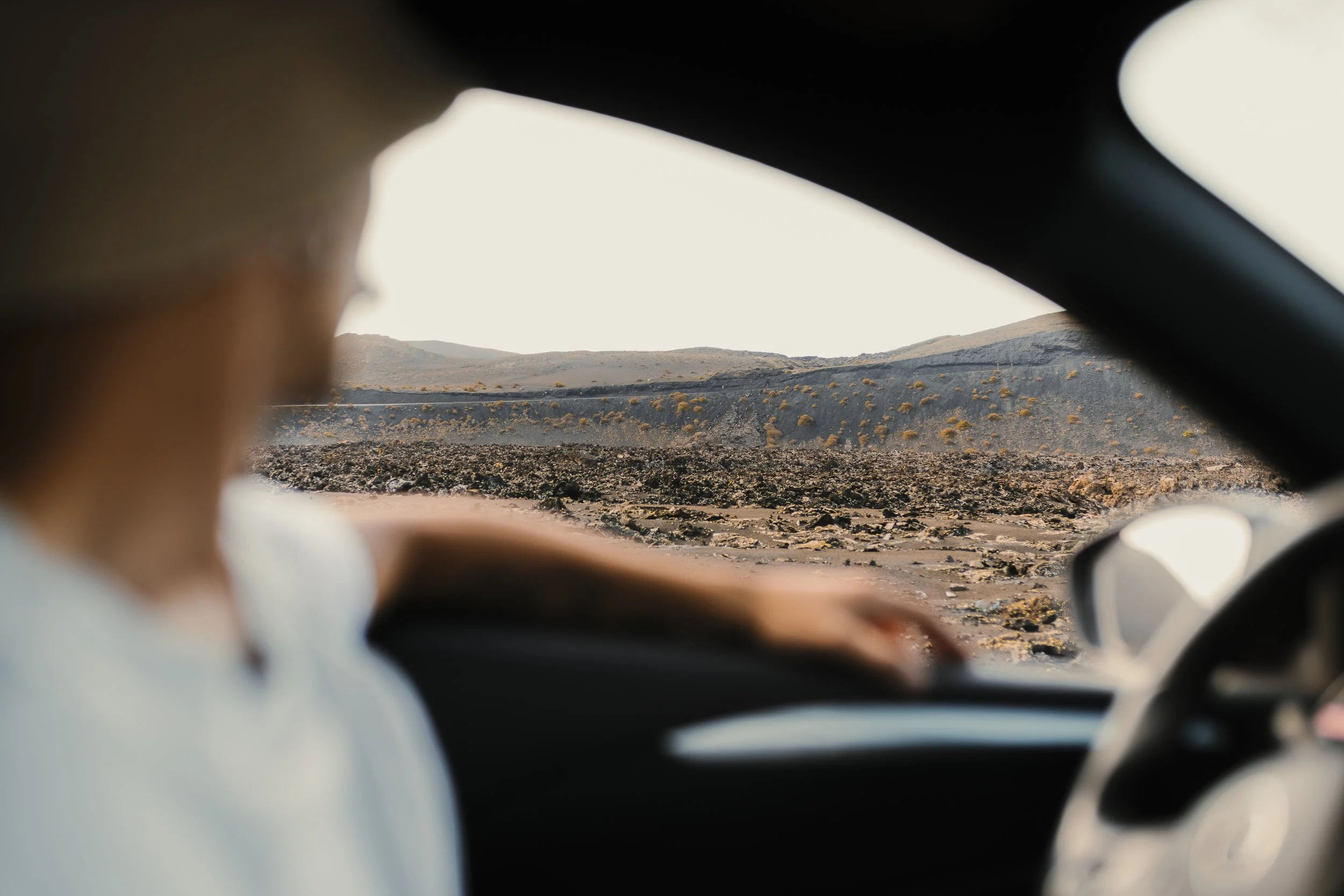 Persona in auto che guarda un paesaggio desertico con colline e rocce