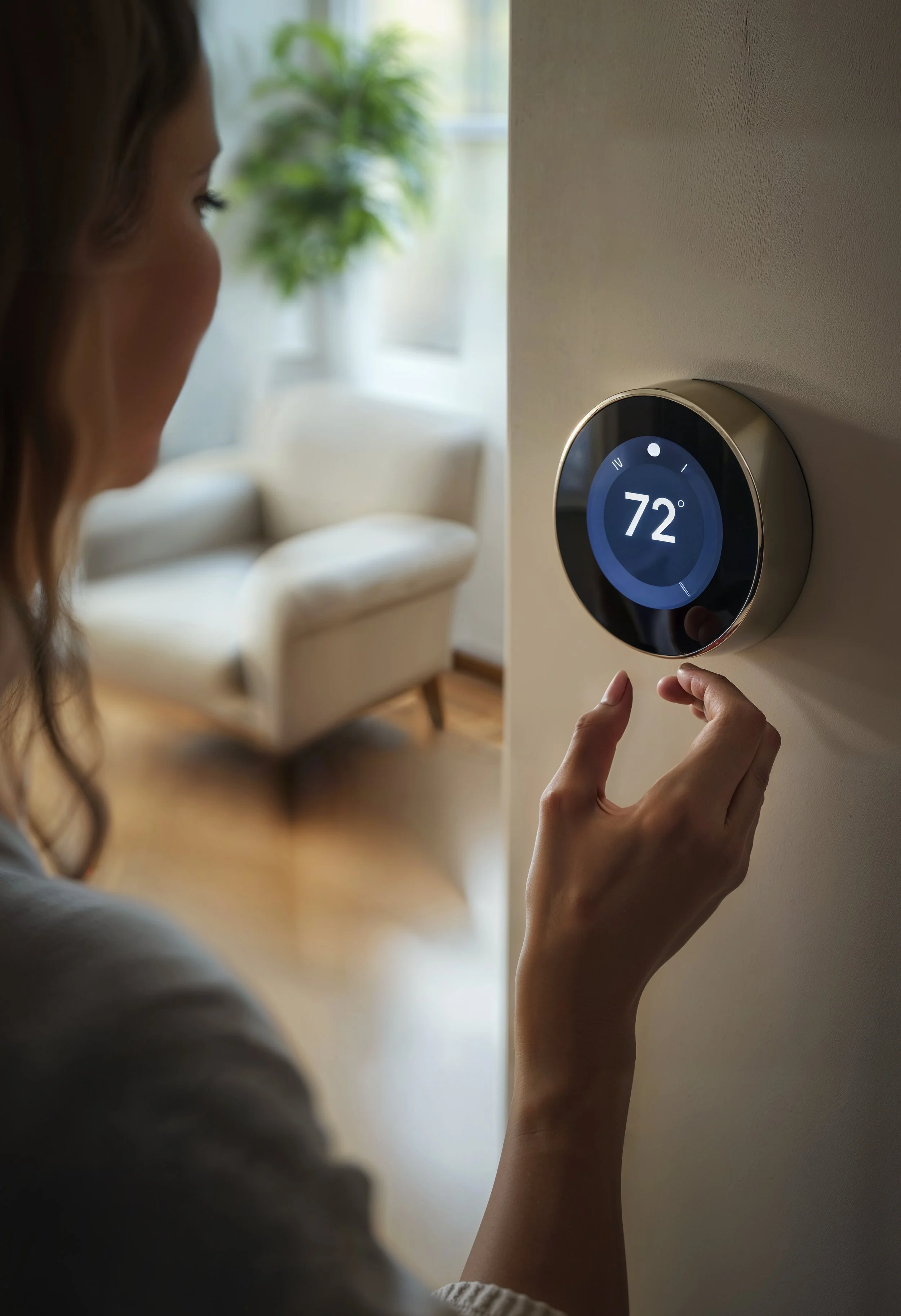 Woman adjusting a smart thermostat on the wall of a home