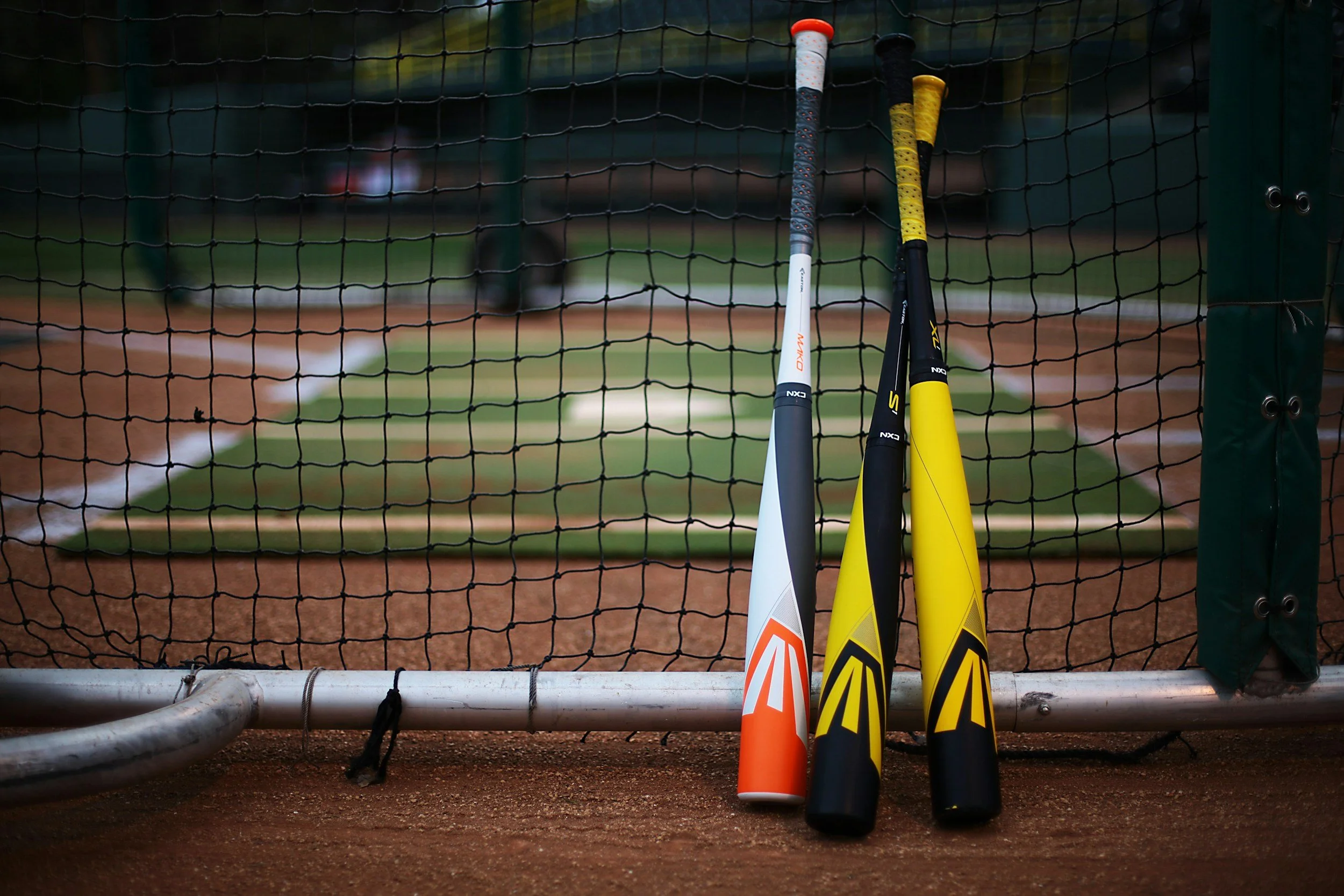 Metal baseball bats outside of a batting cage, a picture by Kenny Nguyễn