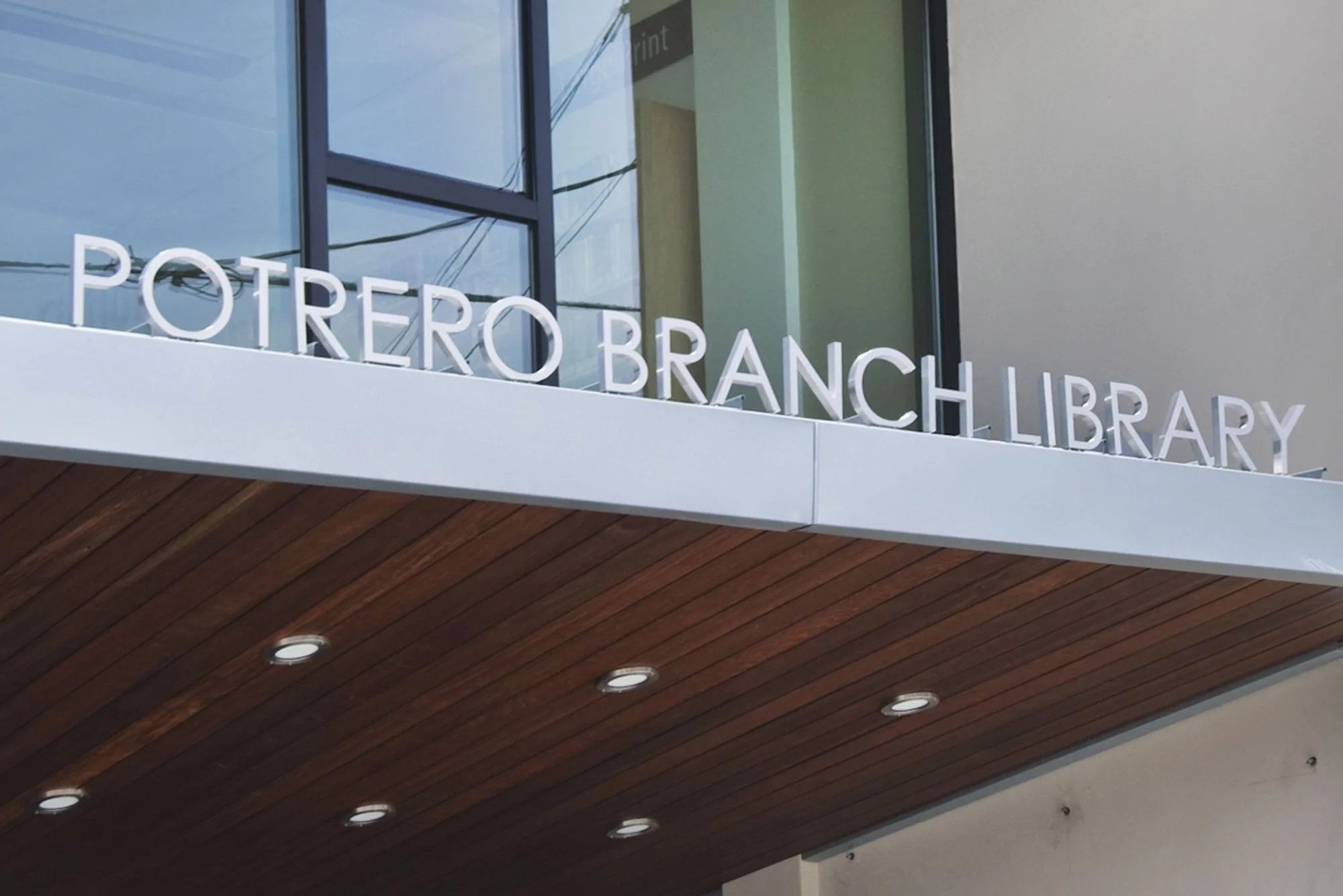 Exterior sign of Potrero Branch Library with large windows and wooden ceiling