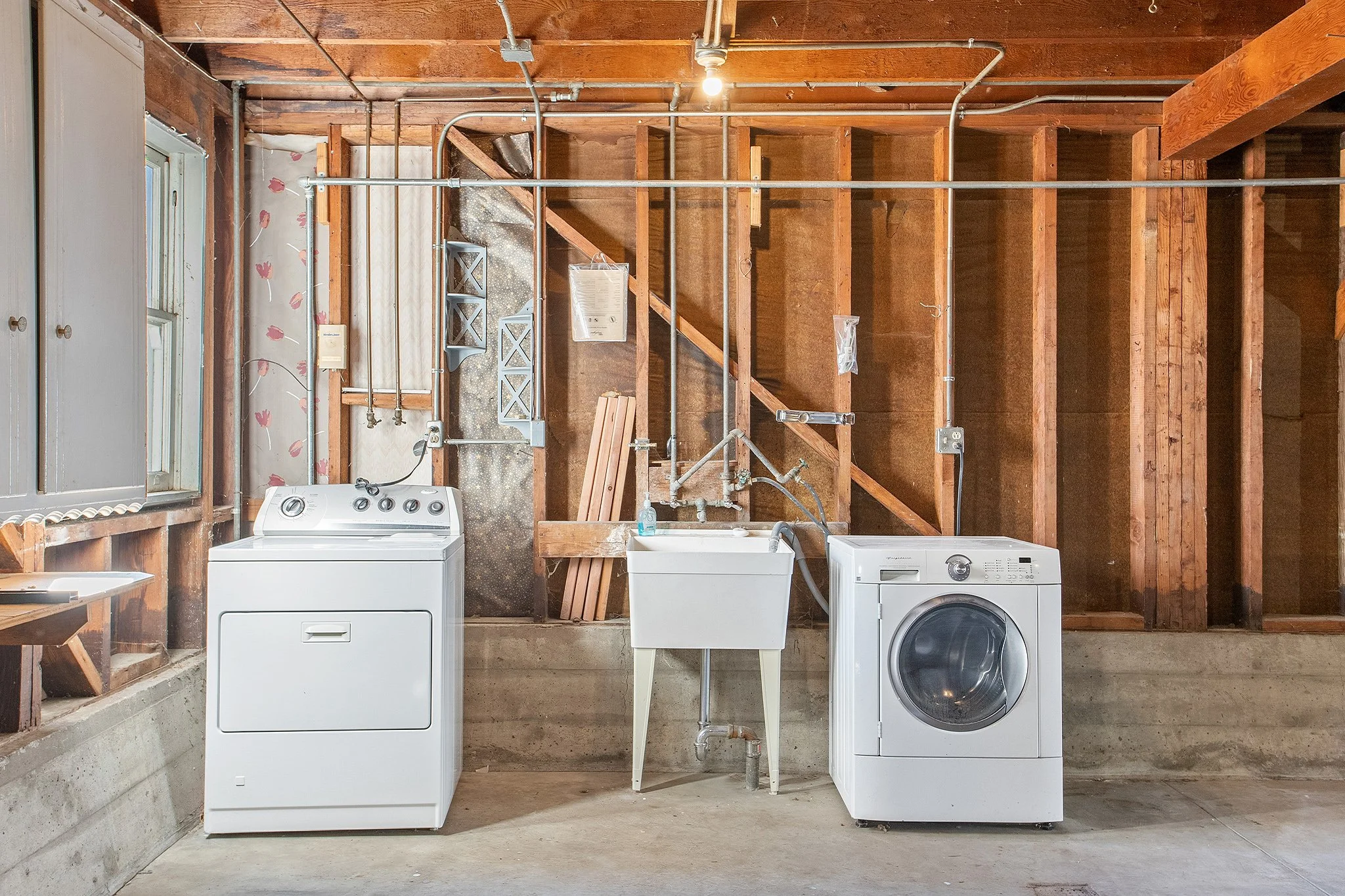 Laundry room with washing machine, dryer, utility sink, and window.