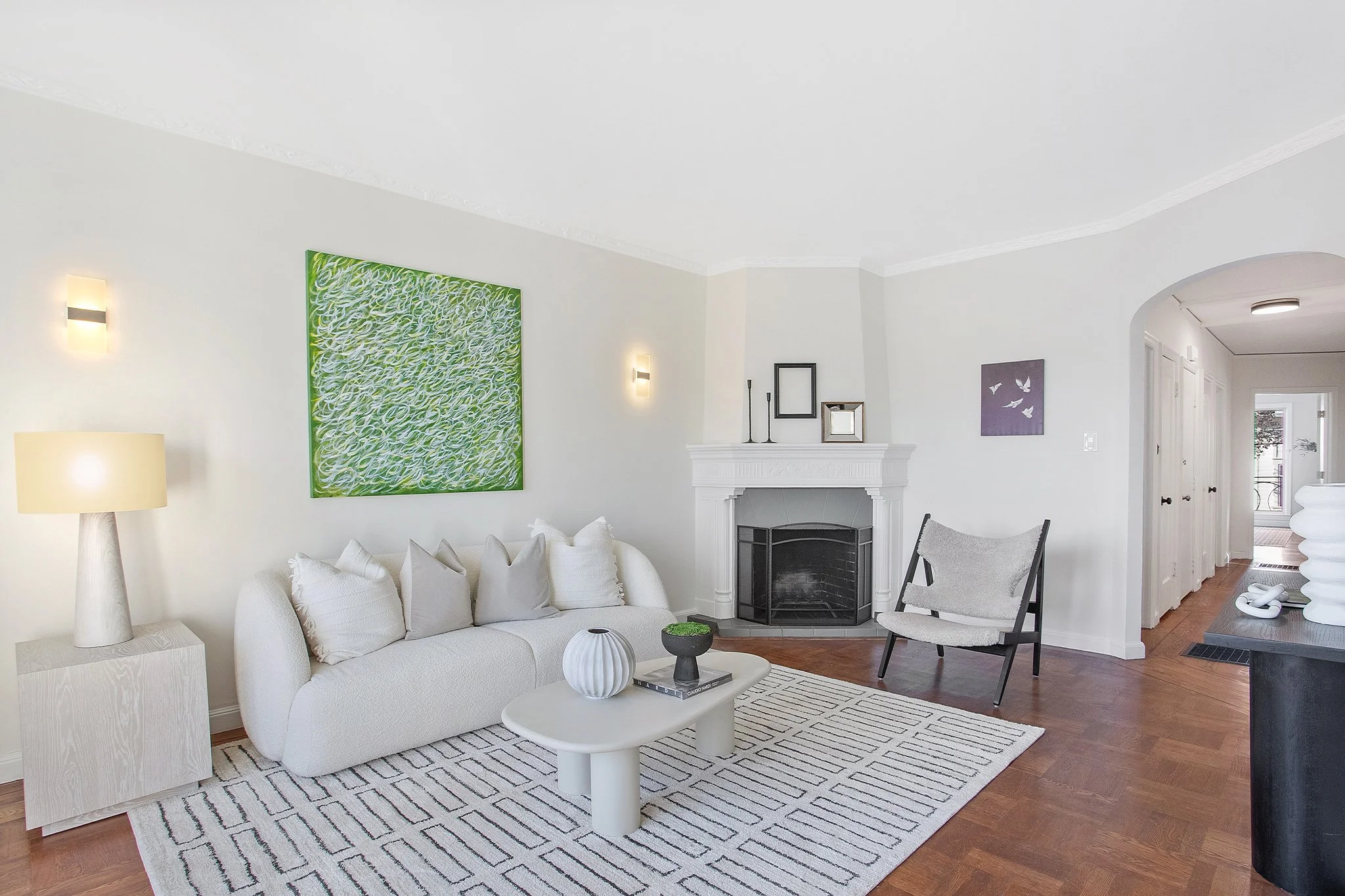 Modern living room with white sofa, coffee table, decorative artwork, and a fireplace.