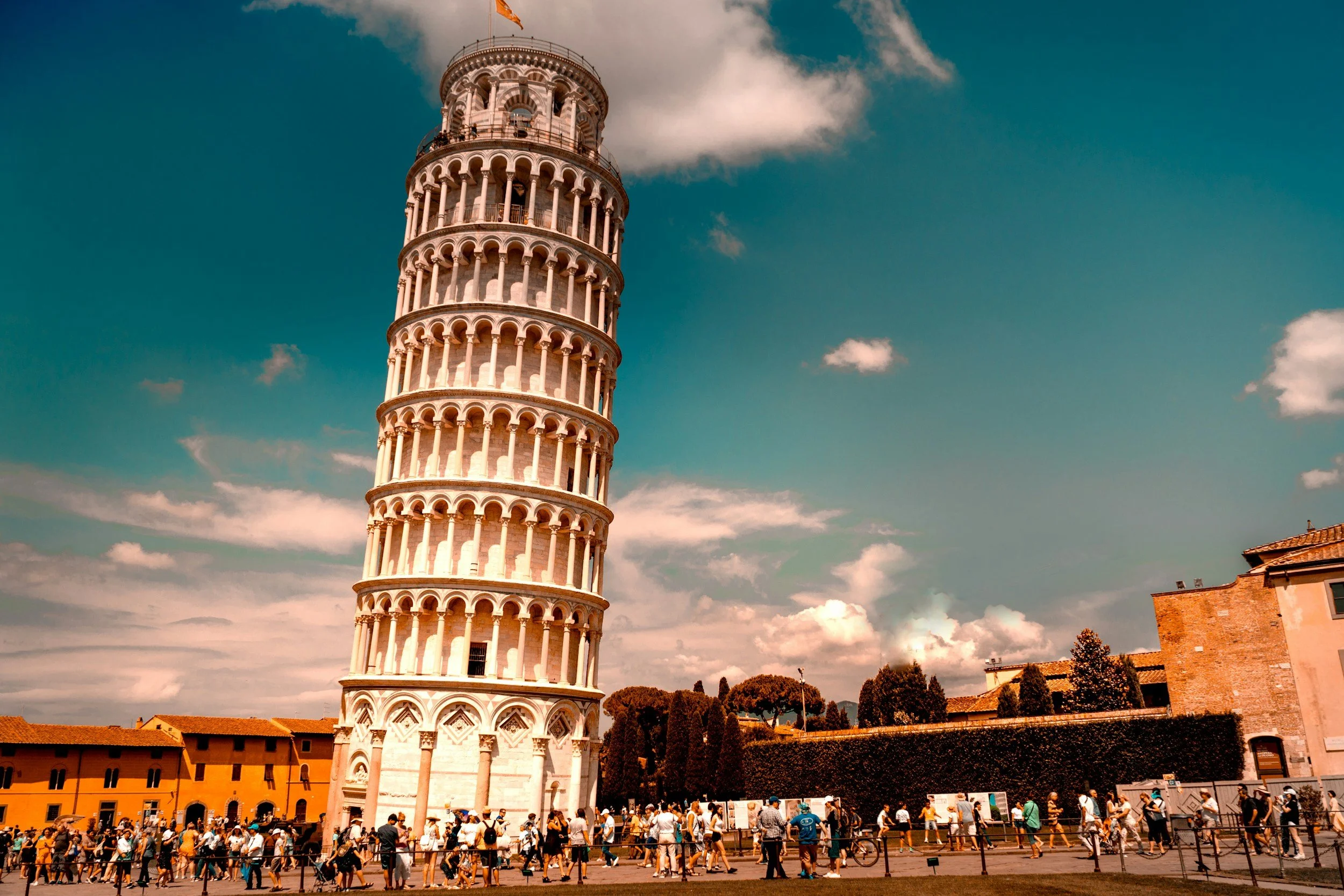The Leaning Tower of Pisa in Pisa, Italy, with tourists gathered around in the foreground.