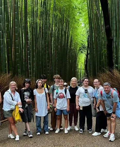 Group of nine people standing on a trail surrounded by tall bamboo trees