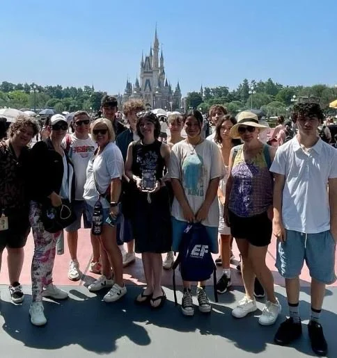 A group of people in front of Cinderella's Castle at a Disney theme park.
