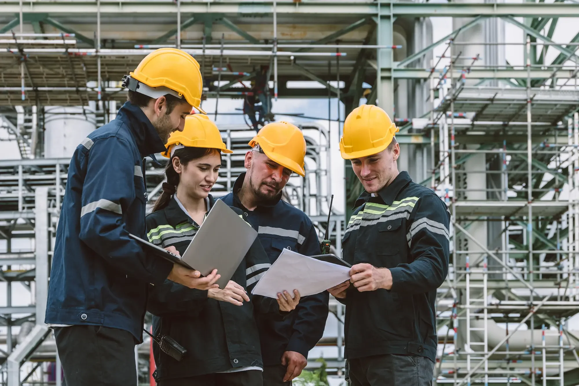 Engineers in hard hats reviewing plans at an industrial site