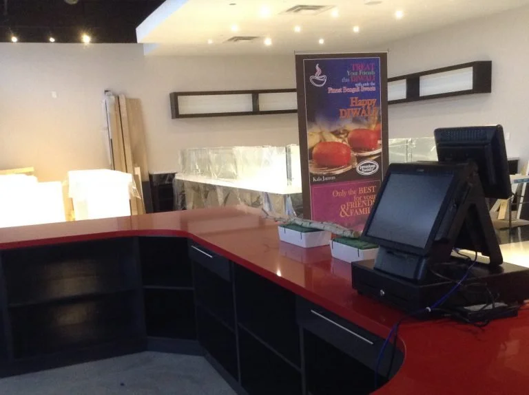 Empty restaurant counter with cash register and promotional poster for a Diwali meal.