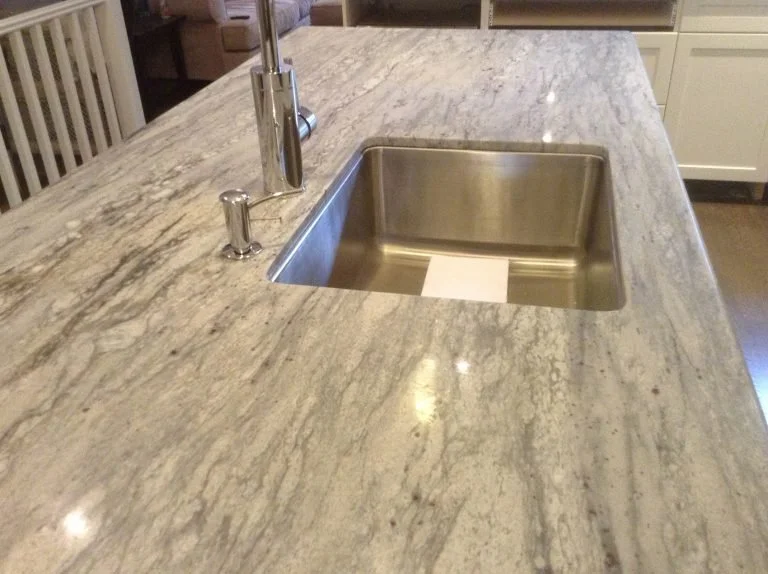 Kitchen island countertop with a stainless steel sink and a modern faucet.