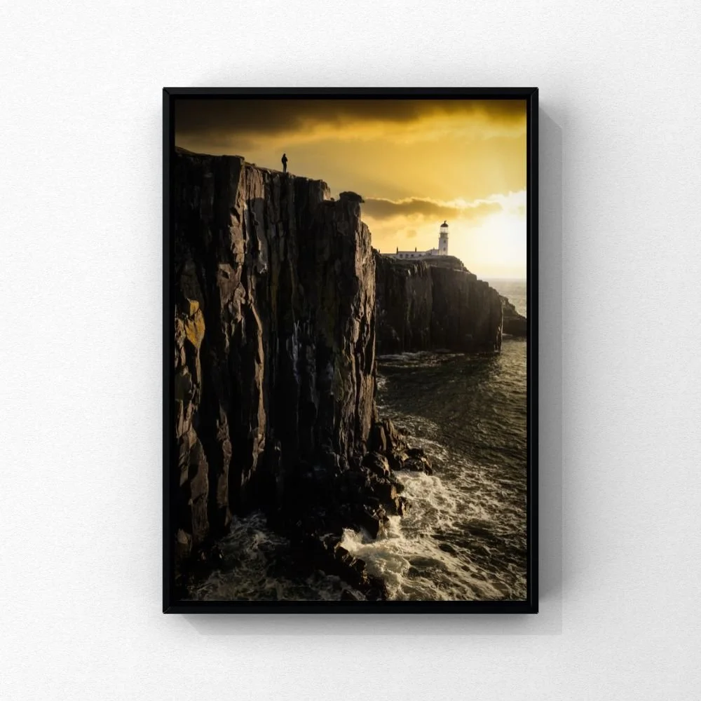 Neist Point lighthouse beyond steep coastal cliffs beneath a golden sky on Skye