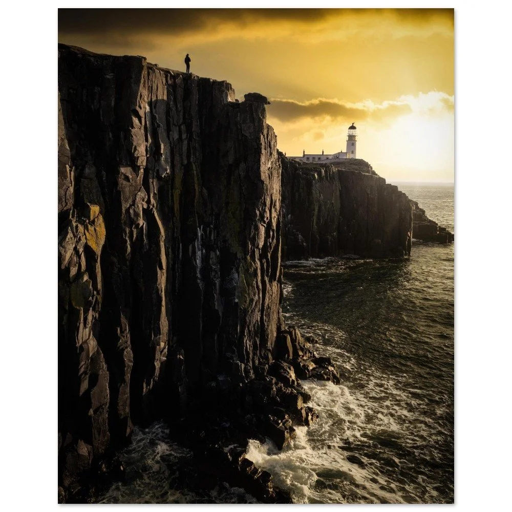 Neist Point lighthouse beyond steep coastal cliffs beneath a golden sky on Skye