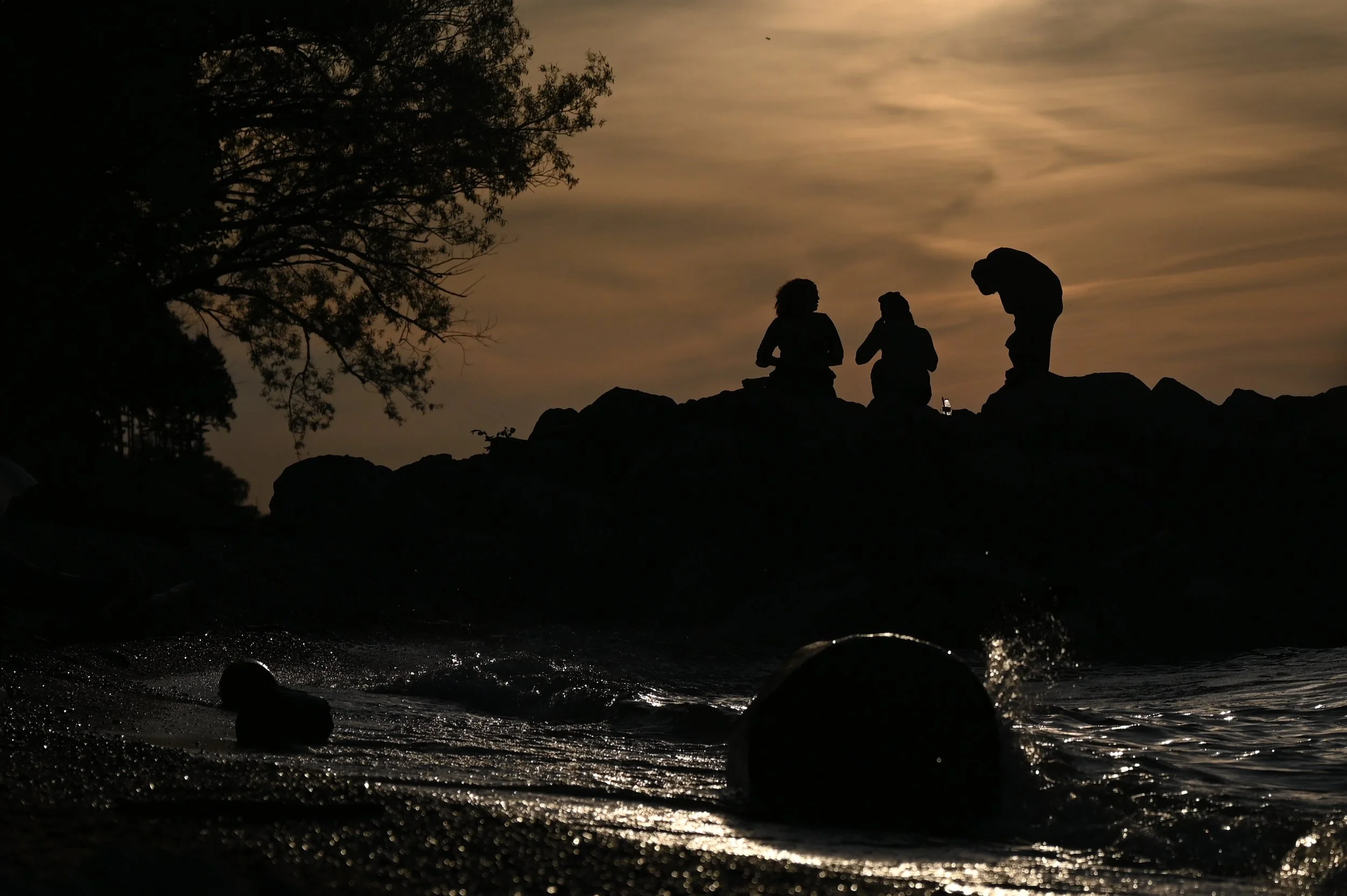 Three beachgoers enjoy the sunset on a groin structure in Lake Erie in Cleveland, Ohio, May 26, 2025.