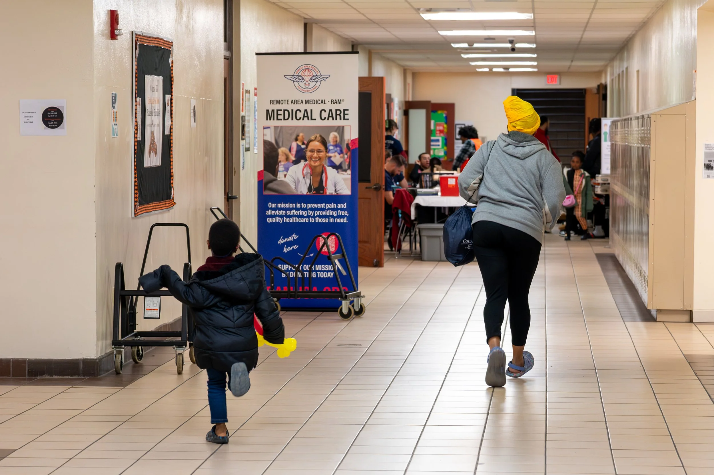 Lu and Davis run down a hall at East High School to get to the medical floor before it closes at a Remote Area Medical clinic in Columbus, Ohio, Nov. 9, 2025.