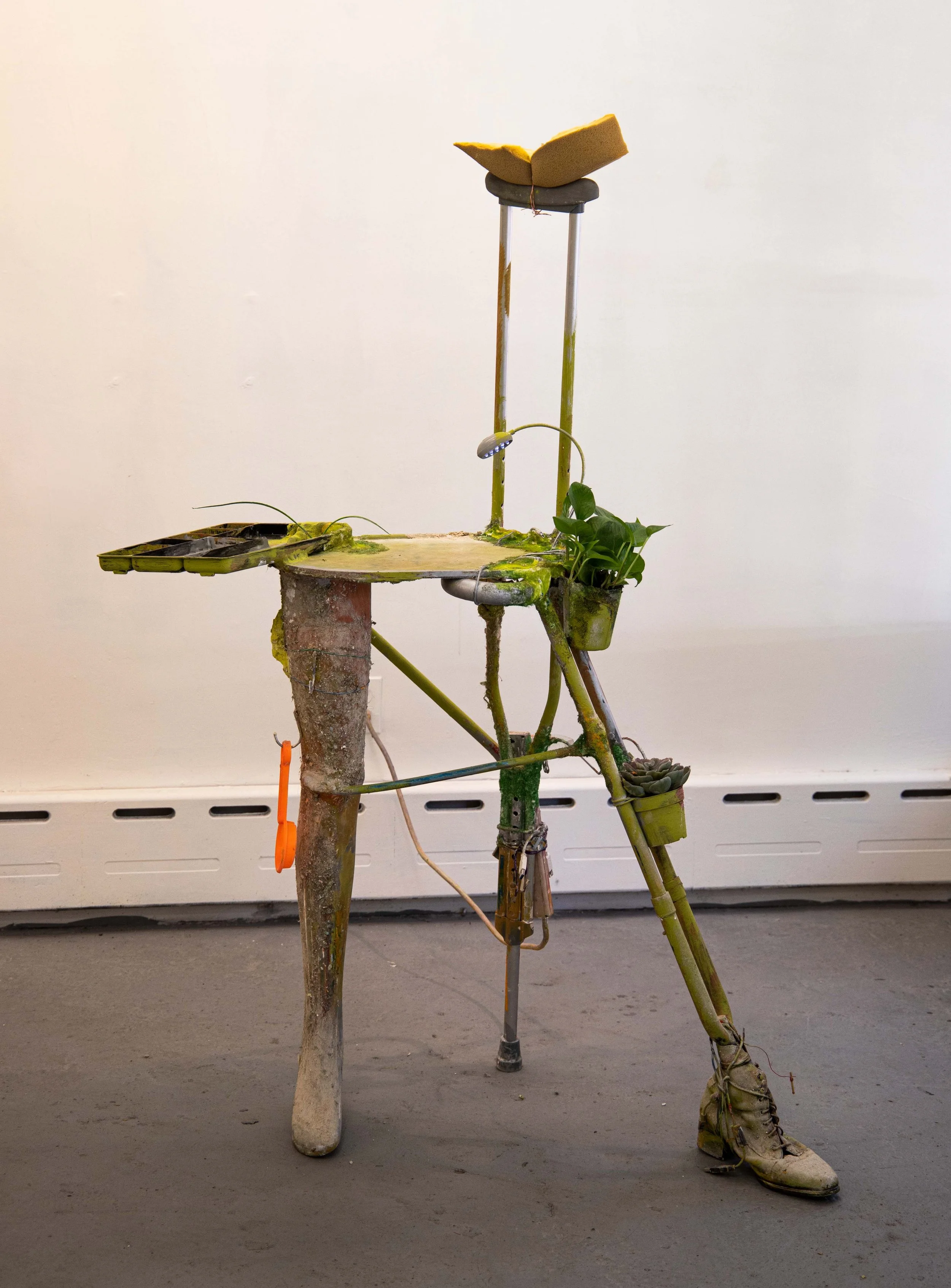Rosalie Smith
Limping Desk
2025
Crutch, mannequin leg, artificial succulent, light, power strip, boot, desk organizer, foam, beach sifter, lanyard, charging cables, hooks, artificial grass, plaster, debris, PVA glue 
62 x 30 x 20 in.
157.5 x 76.2 x 5