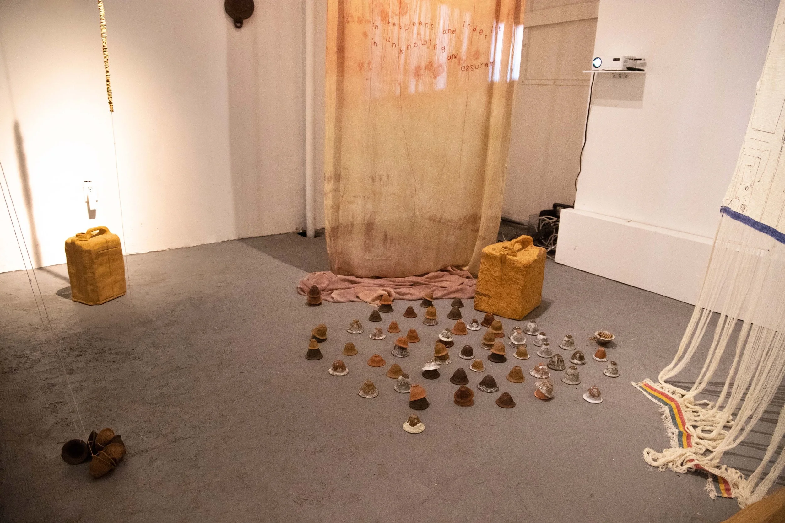 Yeabsera Tabb
Still we are water (2024)
Thread, mud dyed silk, stained muslin from communally shared meals, embroidered poem, hand built clay jugs, wooden bench, poplar, walnut, and pine, video of a performance, chick peas and coffee skins on clay pl