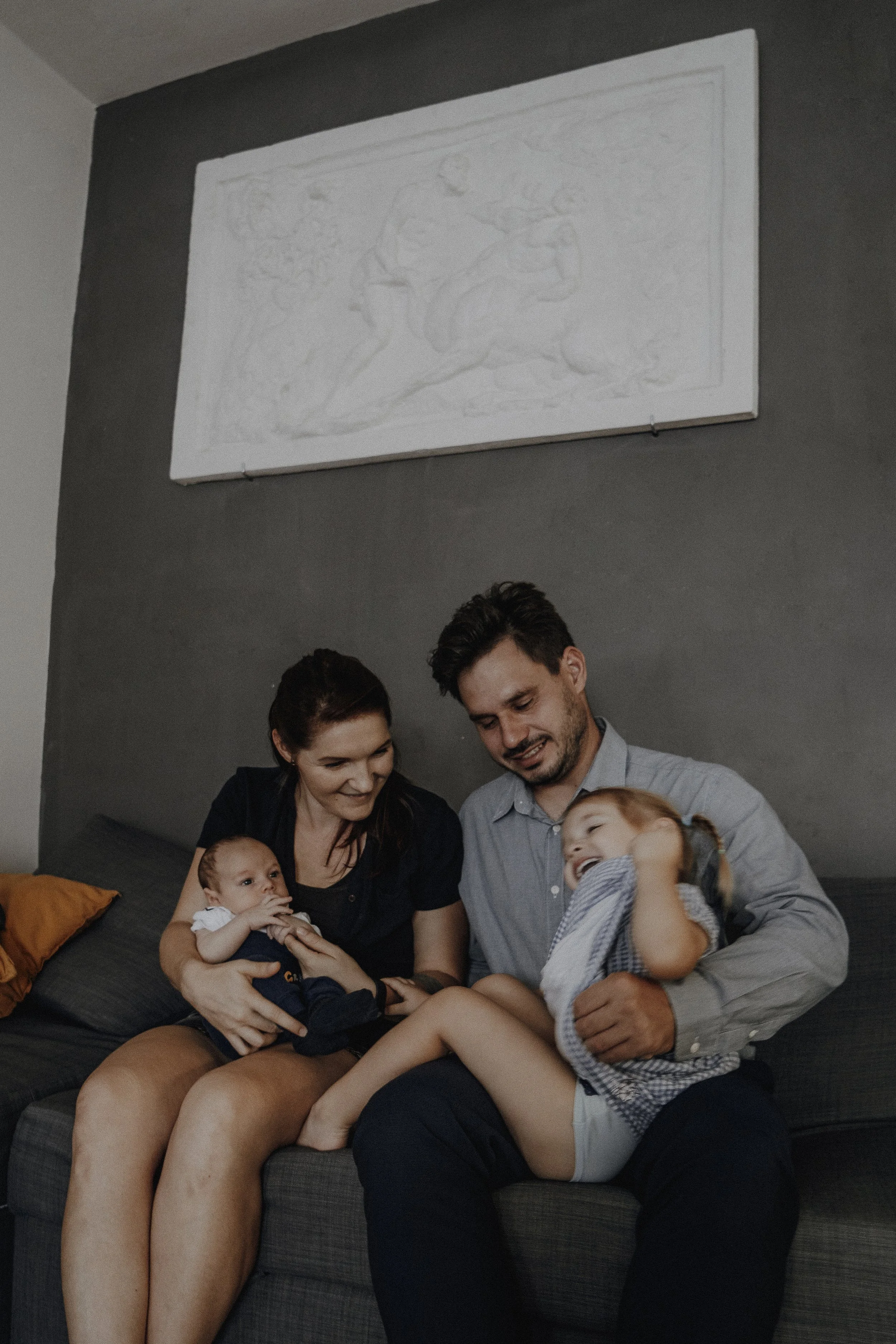 rodinná fotografie na sedačce doma sedí maminka s miminkem a tatínek s dcerou