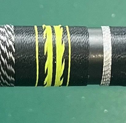 Close-up of a cable or rope with yellow and black markings against a green background.