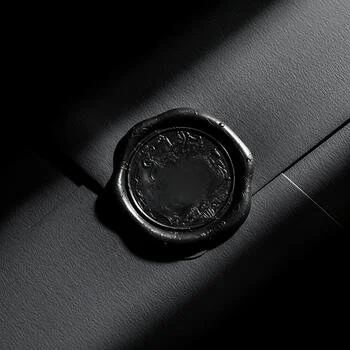 Close-up of a black wax seal on a dark surface with a string attached