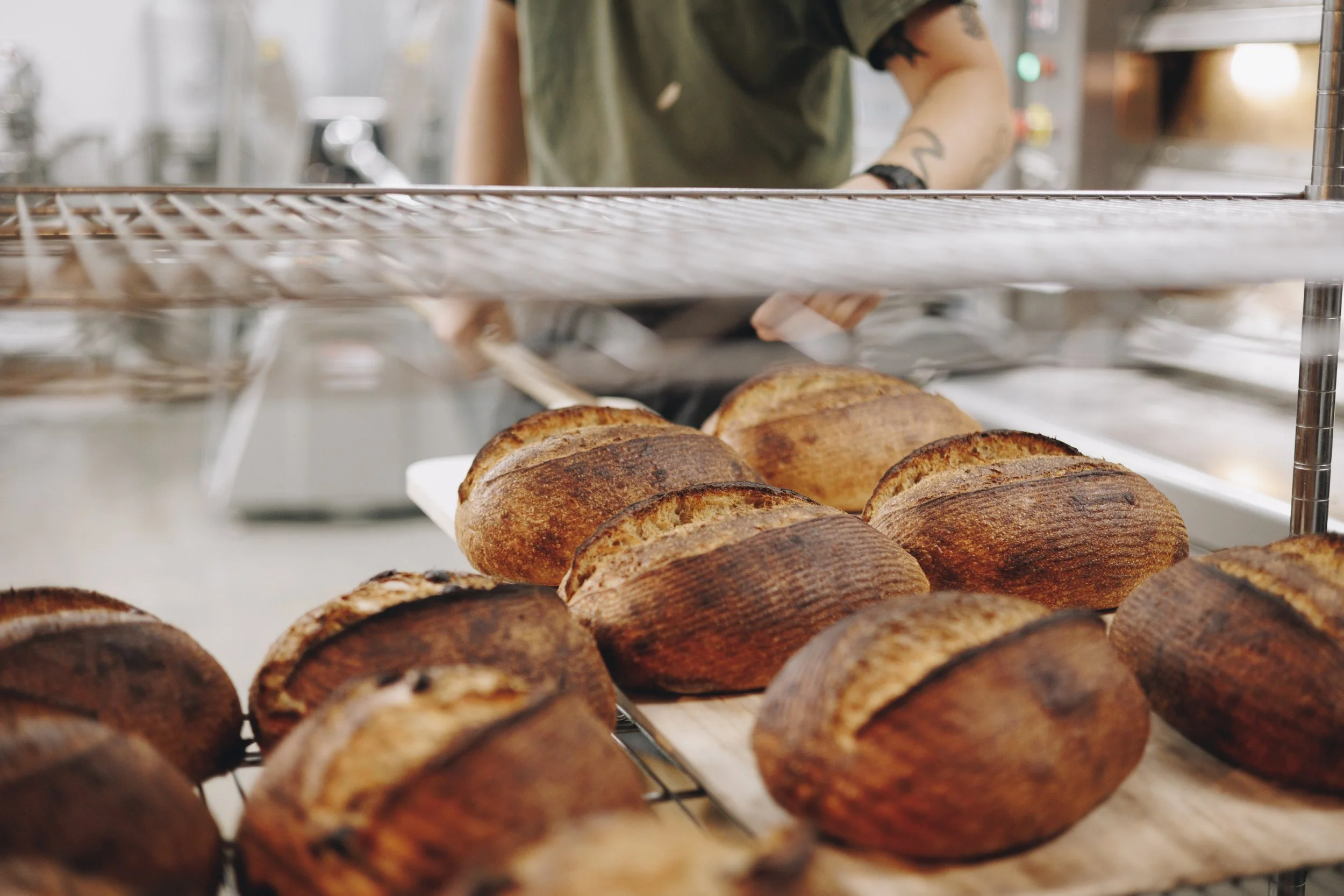 Baked loaves of bread cooling on a rack in a bakery.