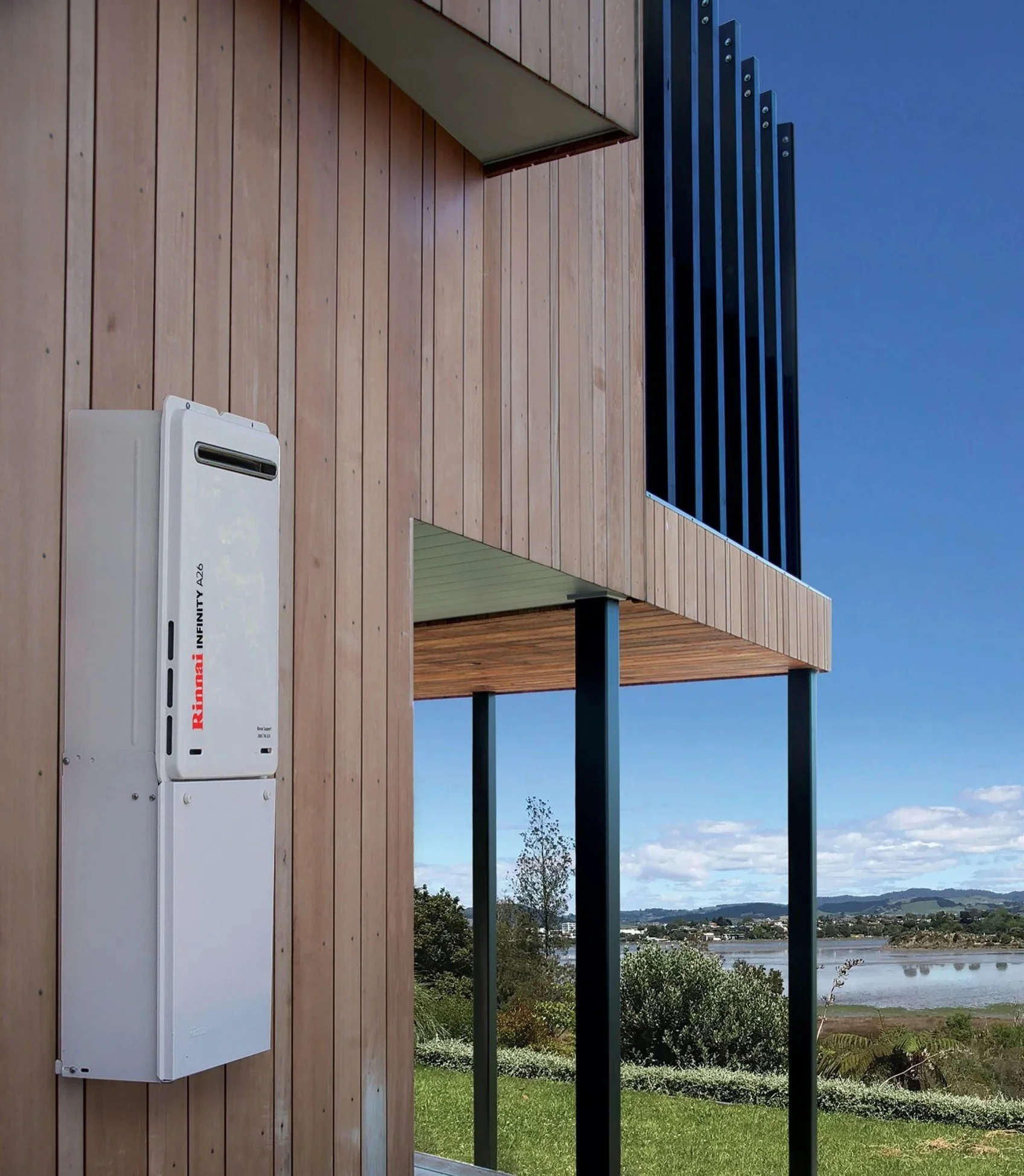 A person installing or repairing a carbon monoxide detector on an outdoor wall near wooden fencing.