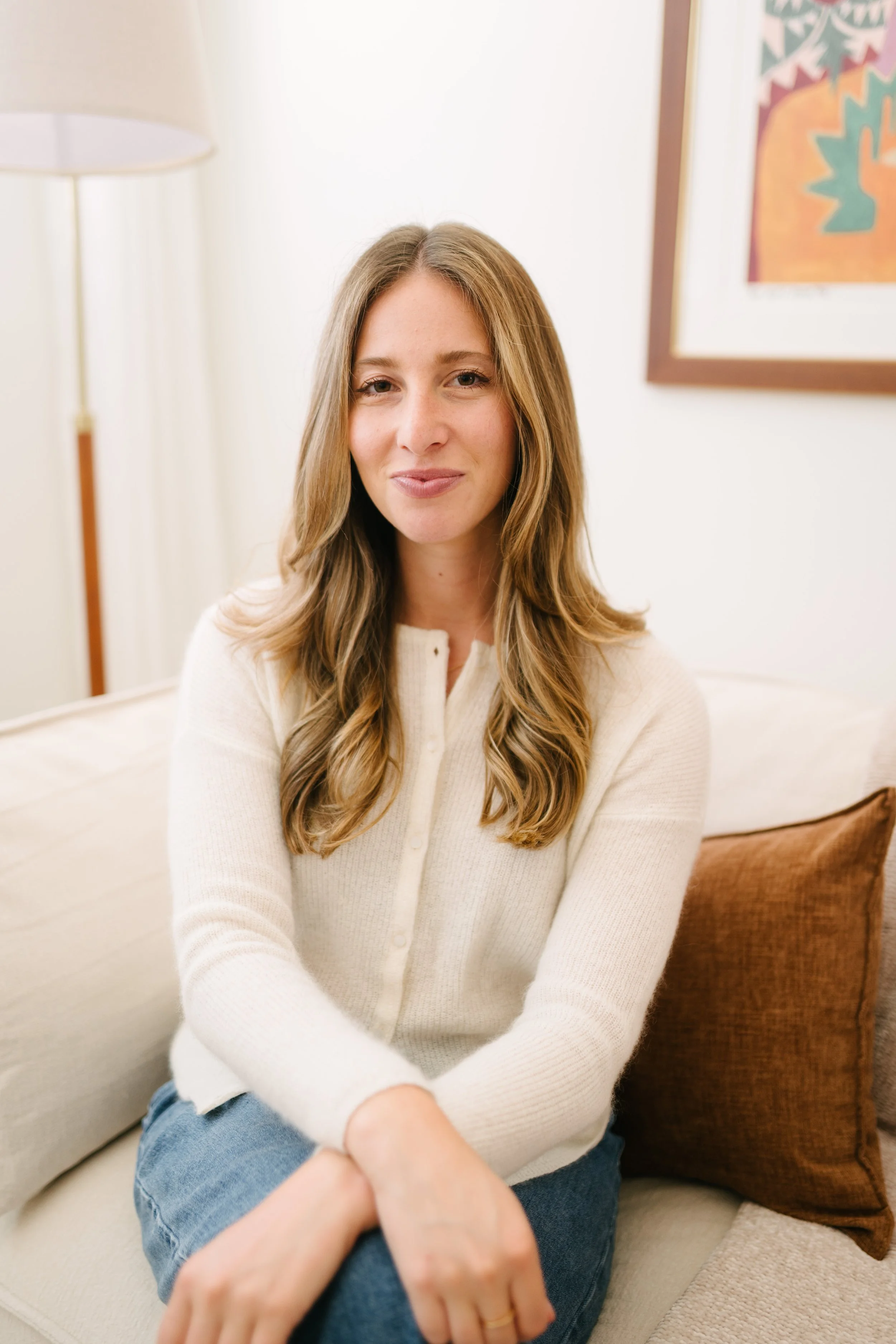 Dr. Brooke Kaufman, PsyD, sitting comfortably on a cream couch in her Los Angeles therapy office.