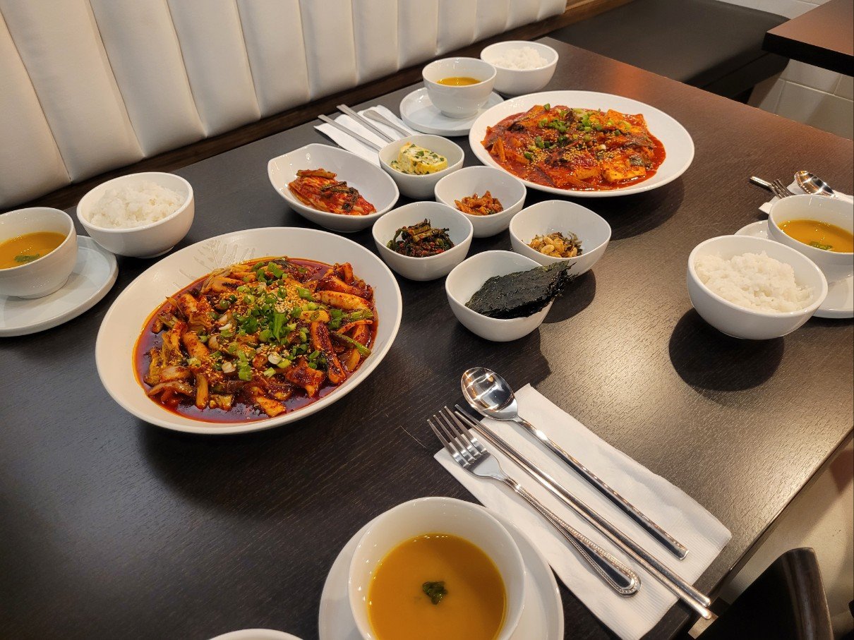 Korean meal with spicy dishes, rice, soup, and various side dishes on a restaurant table.