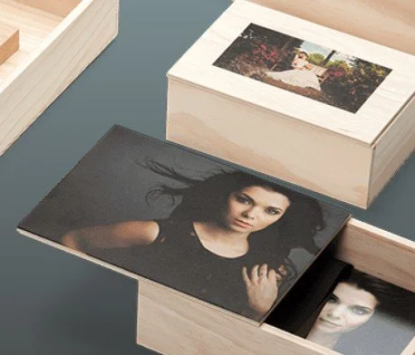 Photographs of a woman, one in color and one in black and white, inside wooden boxes.