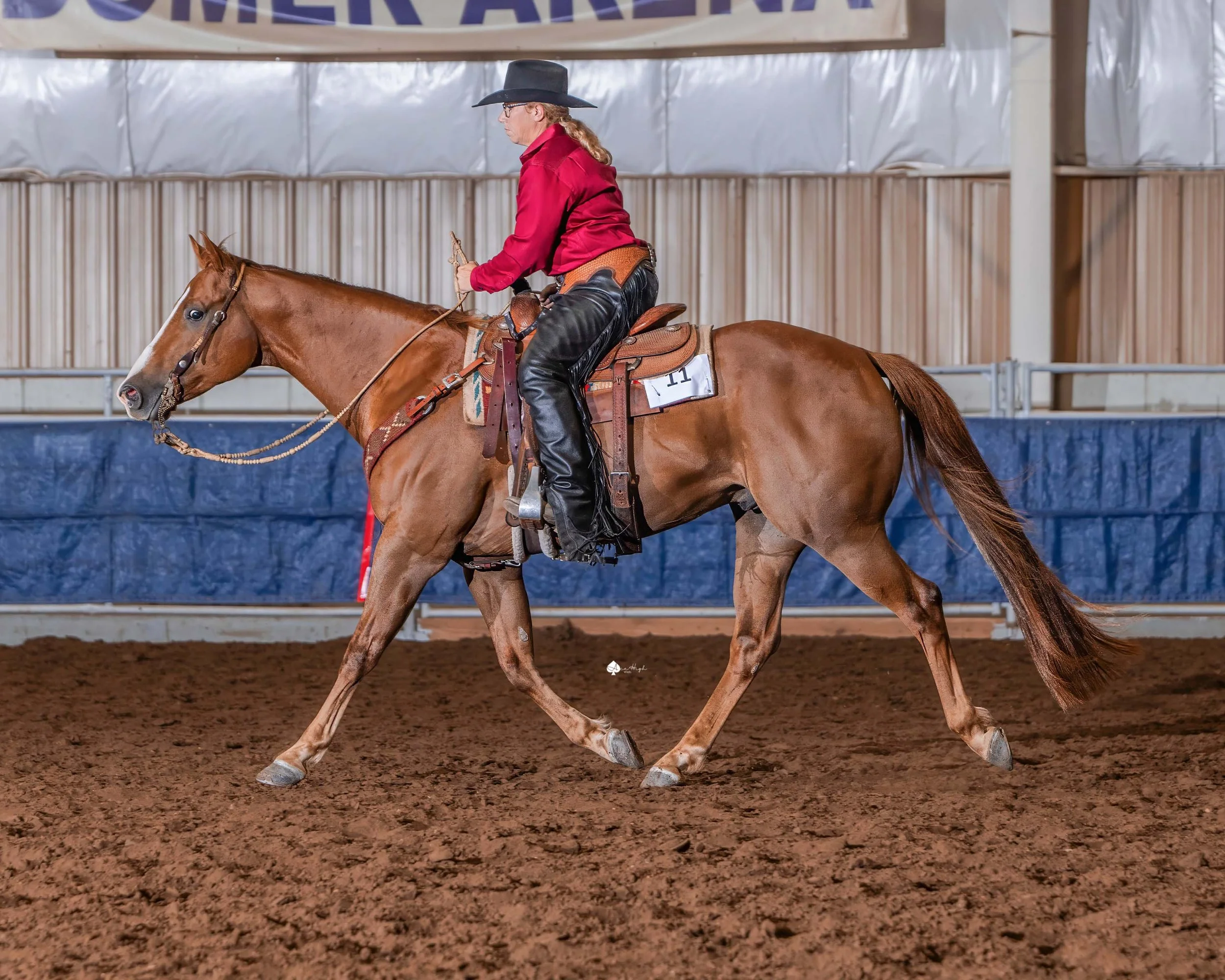 A woman riding a horse in an indoor arena during a rodeo event.