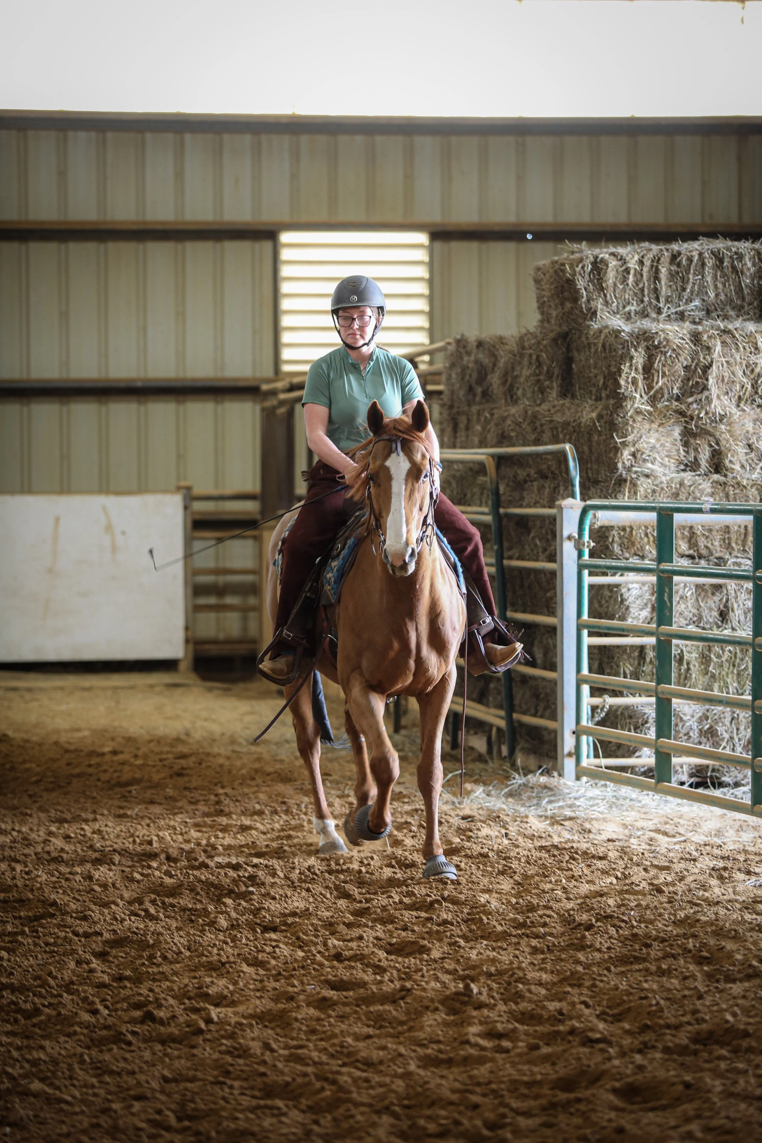 Person riding a horse in an indoor riding arena.